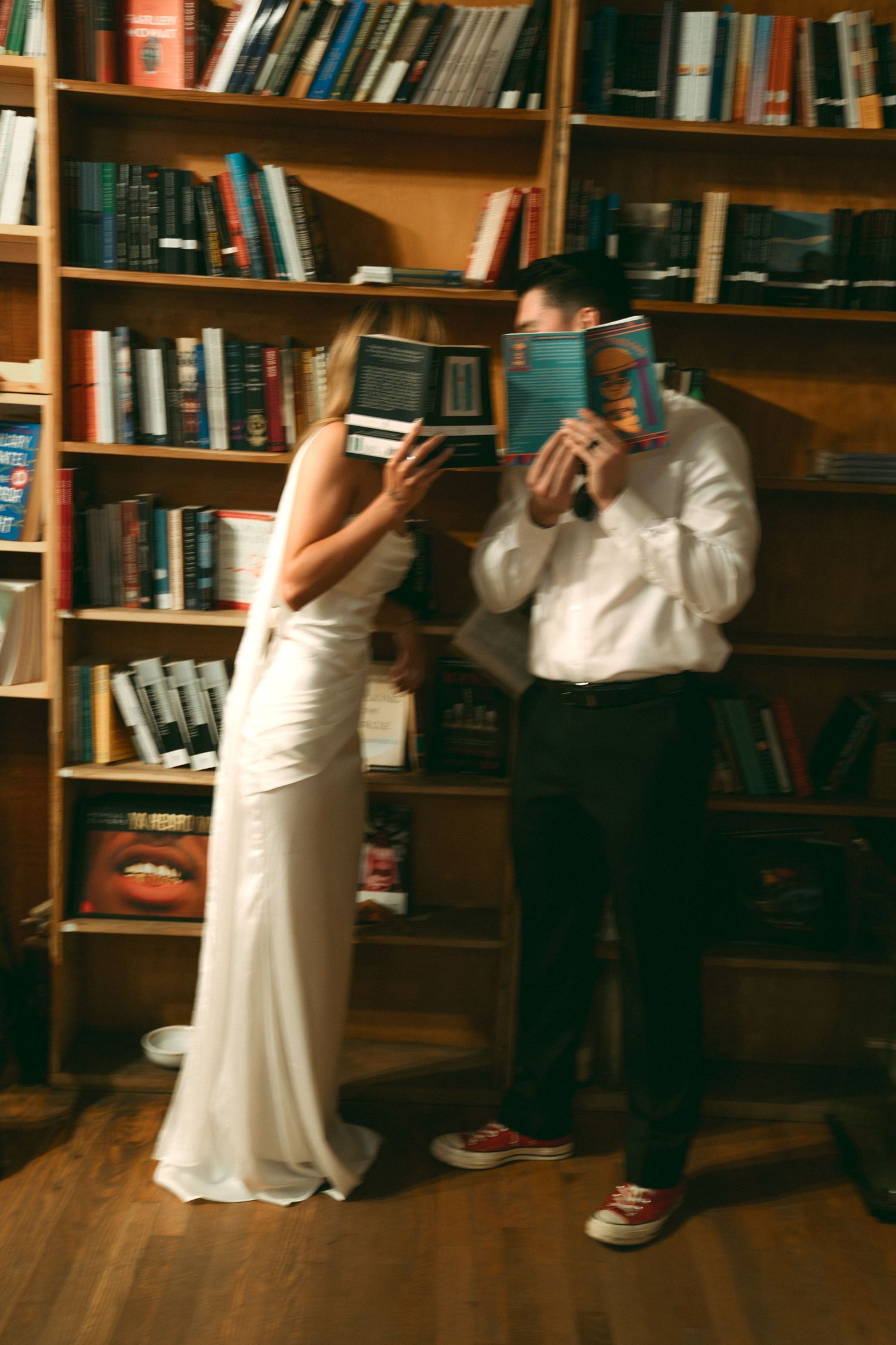 A sequence of people in a library setting showing playful poses against wooden bookshelves.