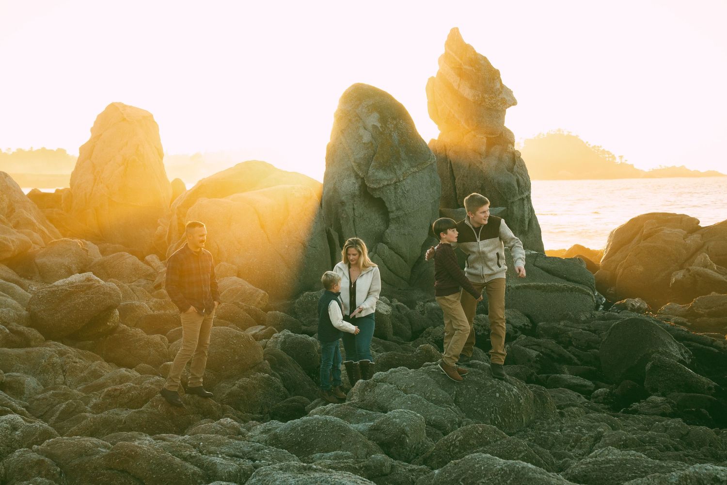 People enjoying a scenic sunset hike along a rocky mountain trail with golden light illuminating the landscape.