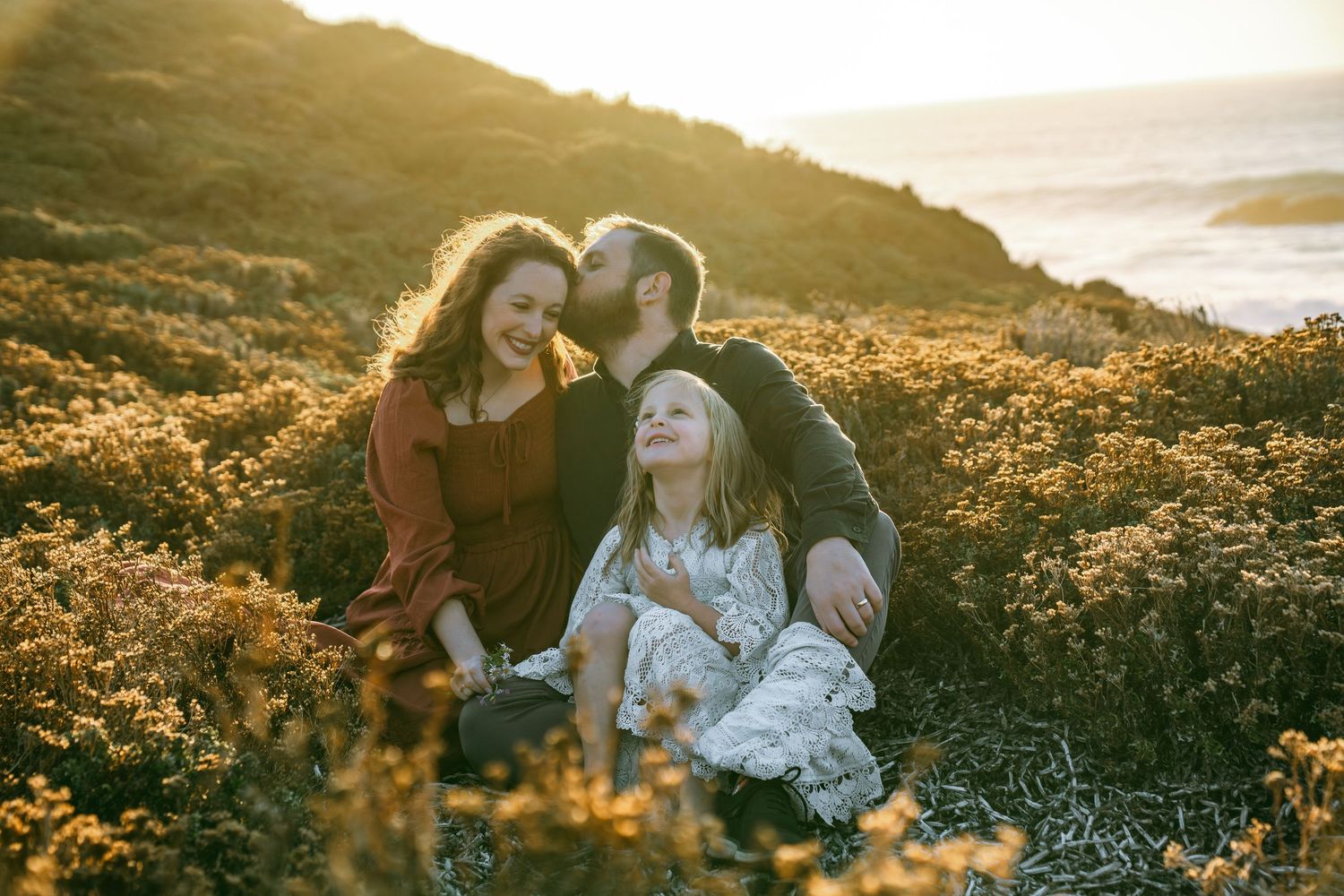 A couple shares a tender moment in a field of wildflowers during golden hour sunset.