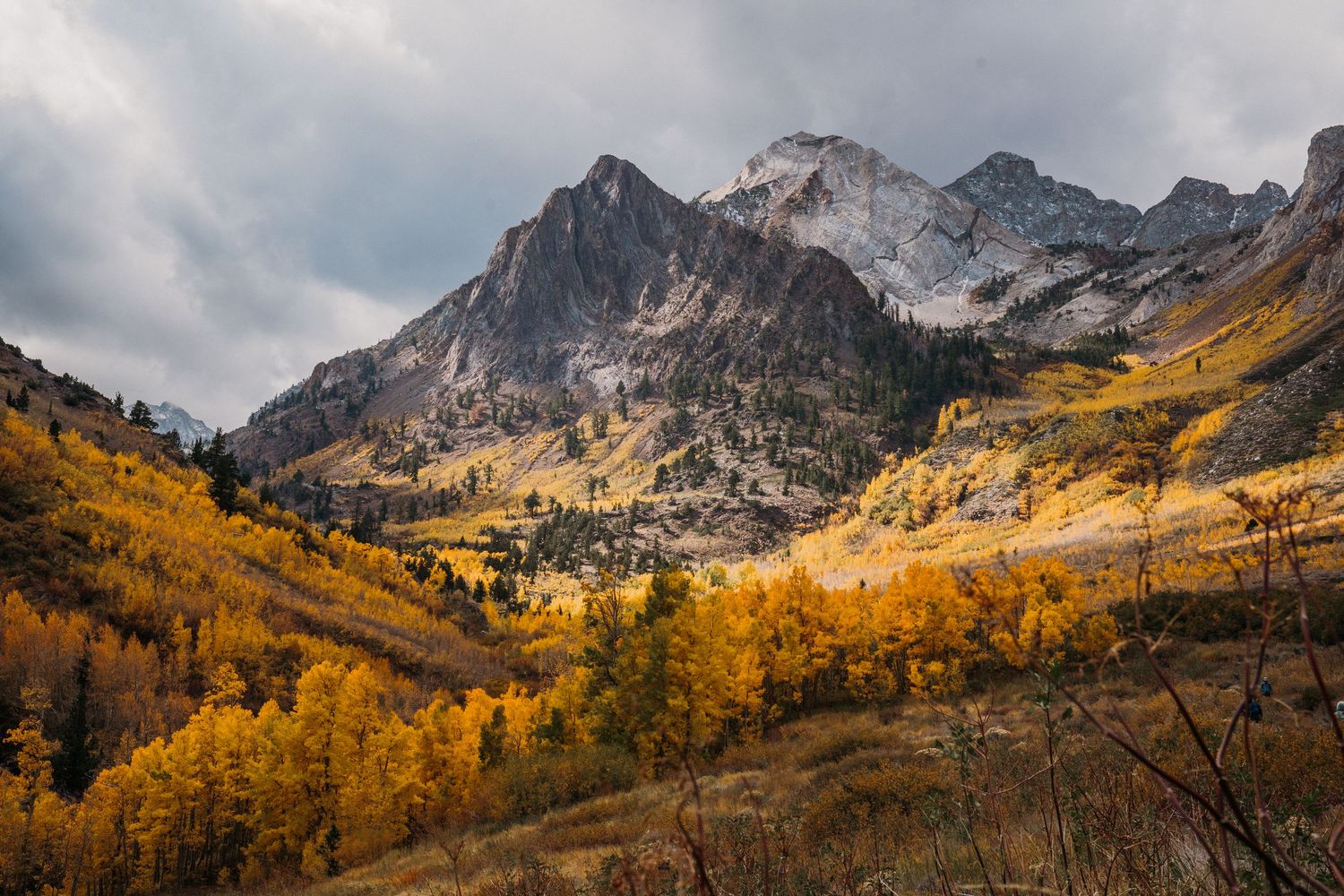 Panoramic mountain landscape with golden aspen trees and snow-dusted peaks in autumn at Maroon Bells, Colorado.