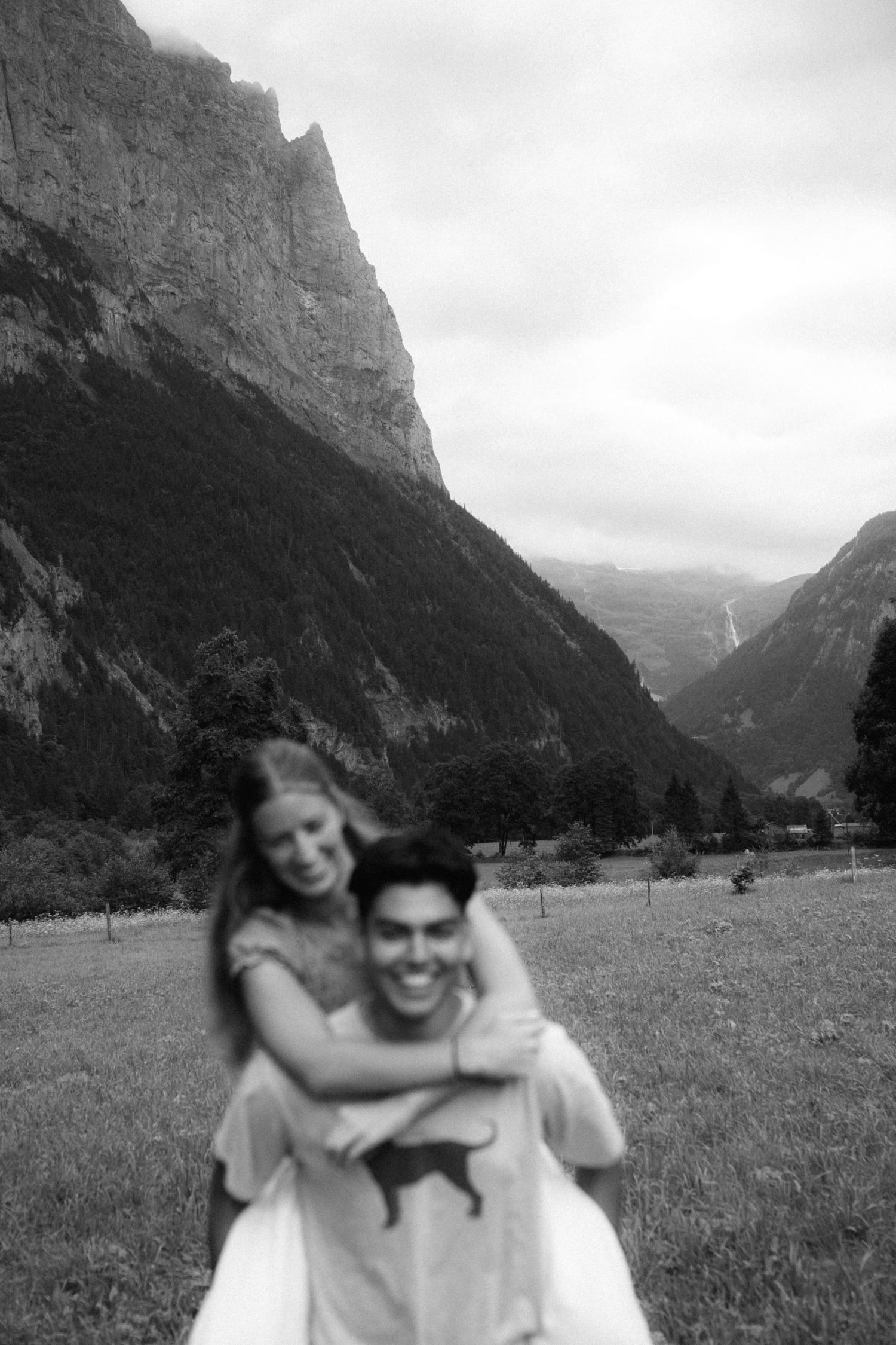 People sharing a playful moment in a scenic mountain valley meadow.