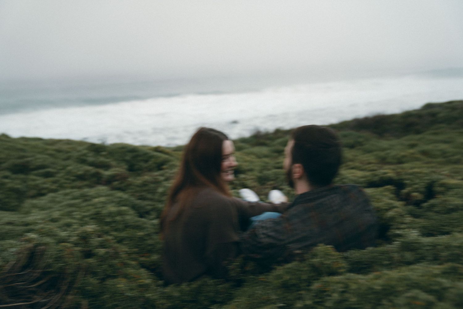 Couple enjoying scenic moments together on coastal mountainside.