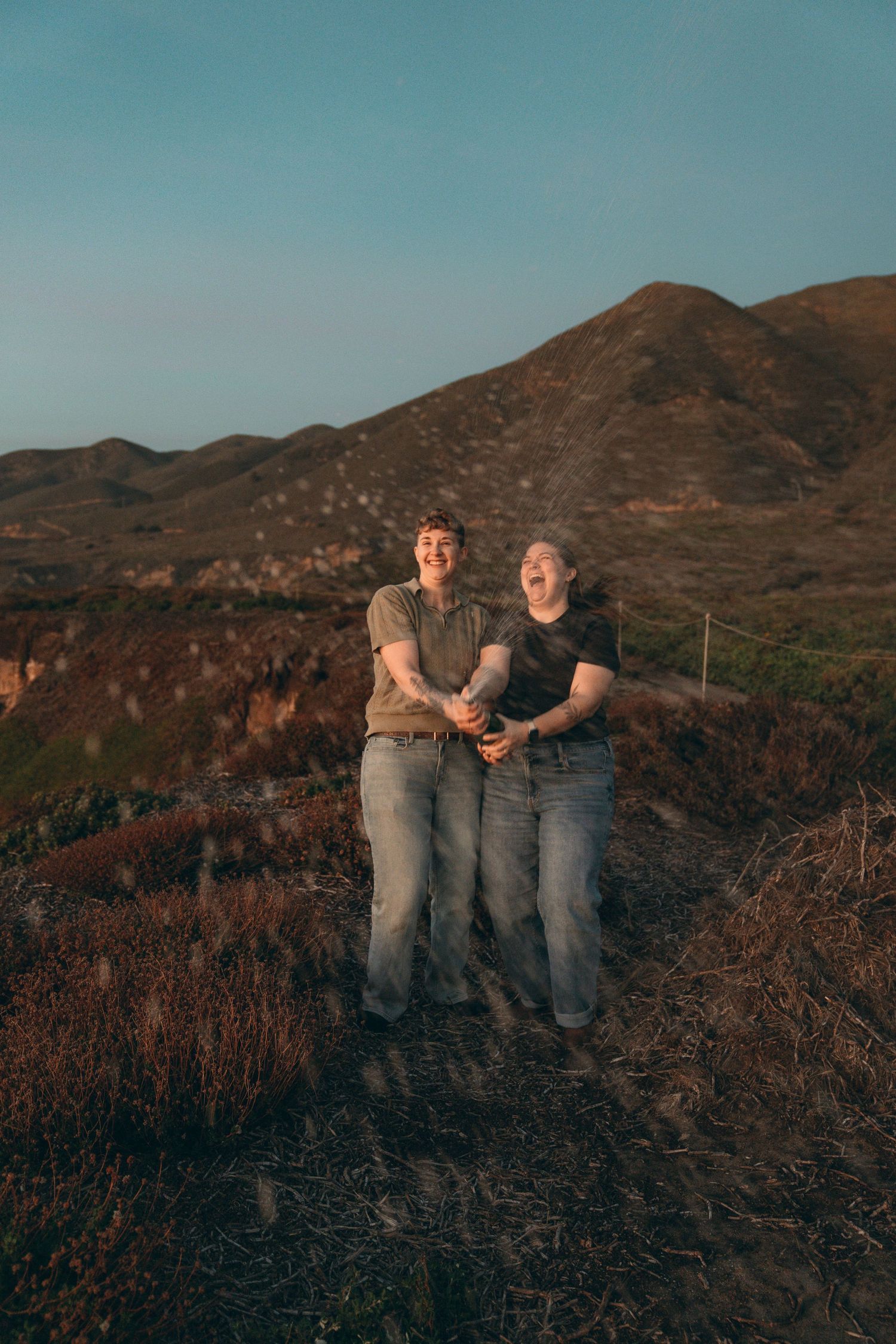 Couple spraying champagne to celebrate their engagement in Big Sur