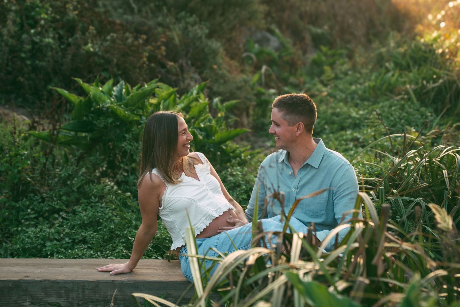 Couple relaxing together in a lush green garden setting during sunset.