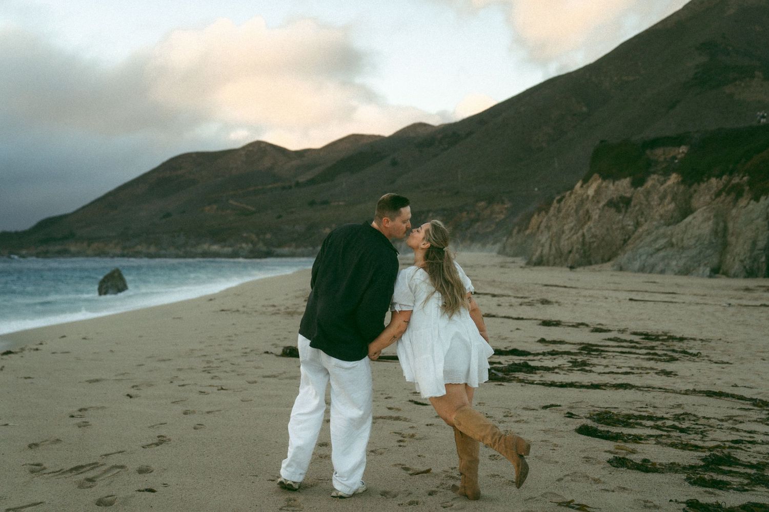 Romantic walk along a scenic beach with mountains and cliffs as a dramatic backdrop.