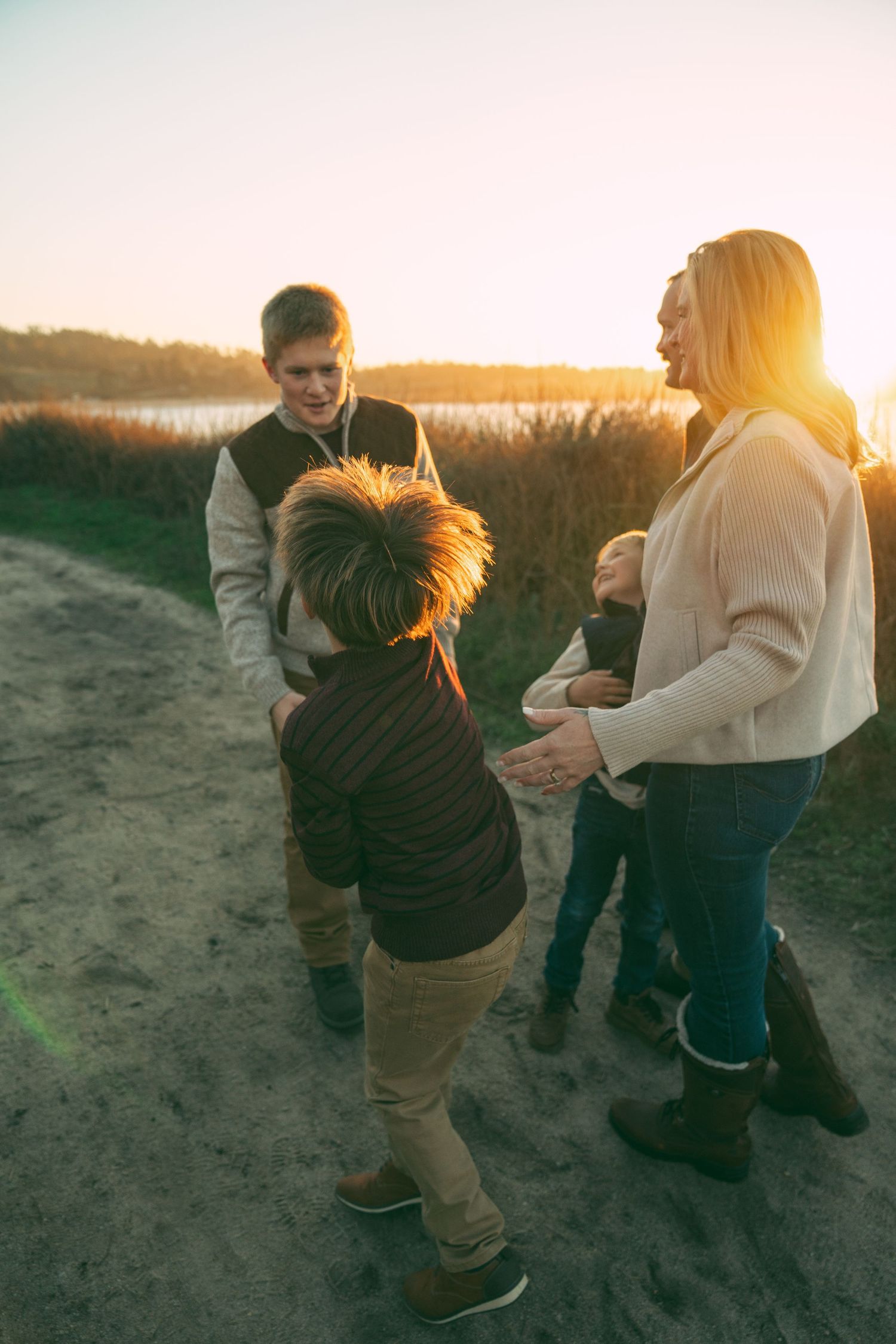 Family enjoying a sunset walk along a sandy beach path with warm evening light.