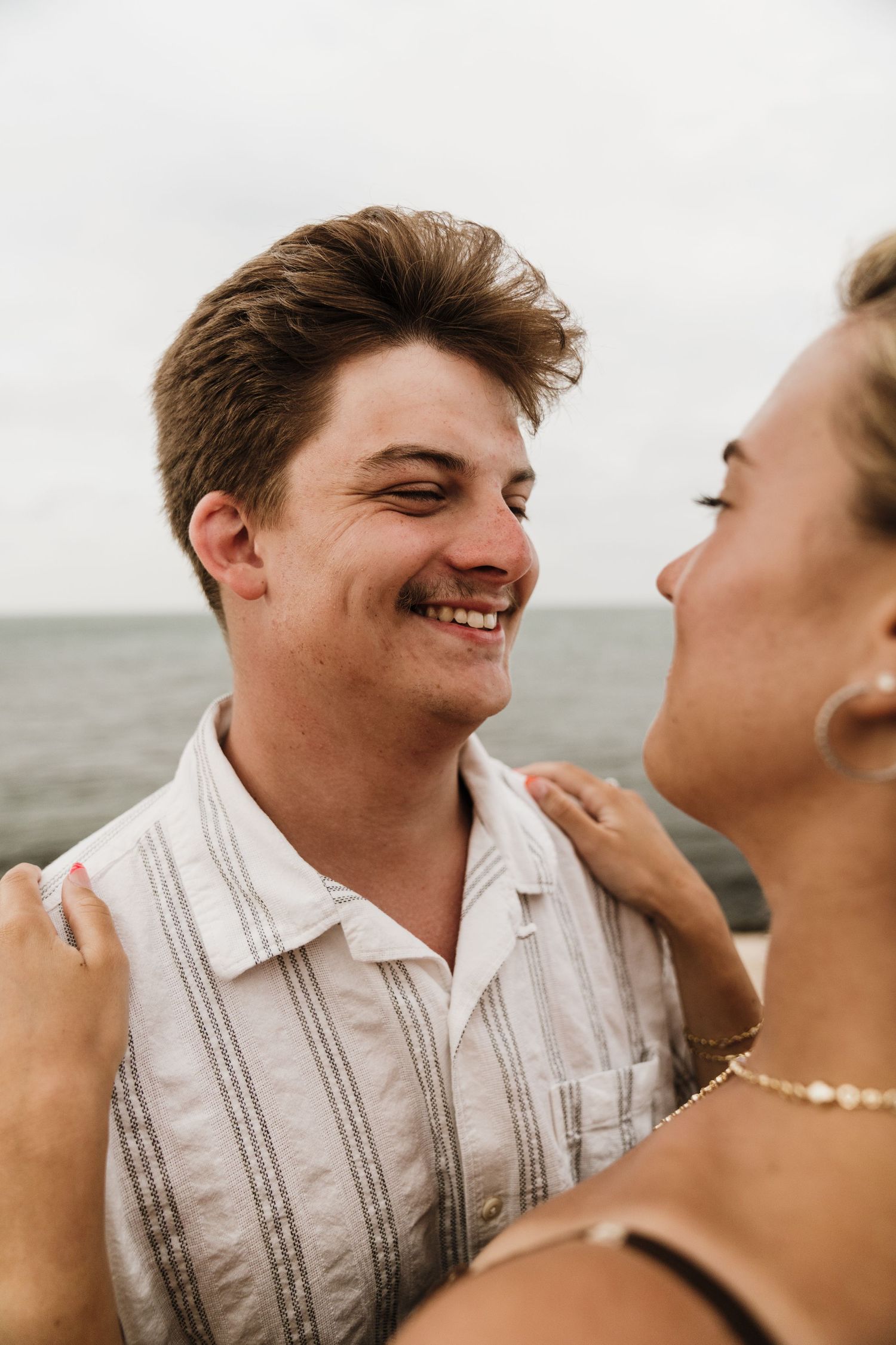 A joyful moment shared between a couple laughing together by the ocean.