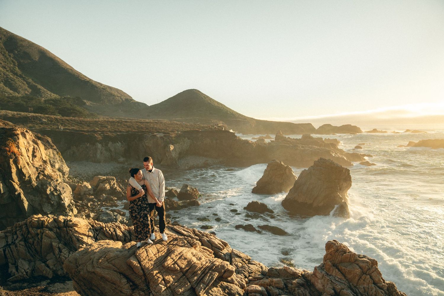 Dramatic coastal landscape with waves crashing against rocky cliffs during golden hour.