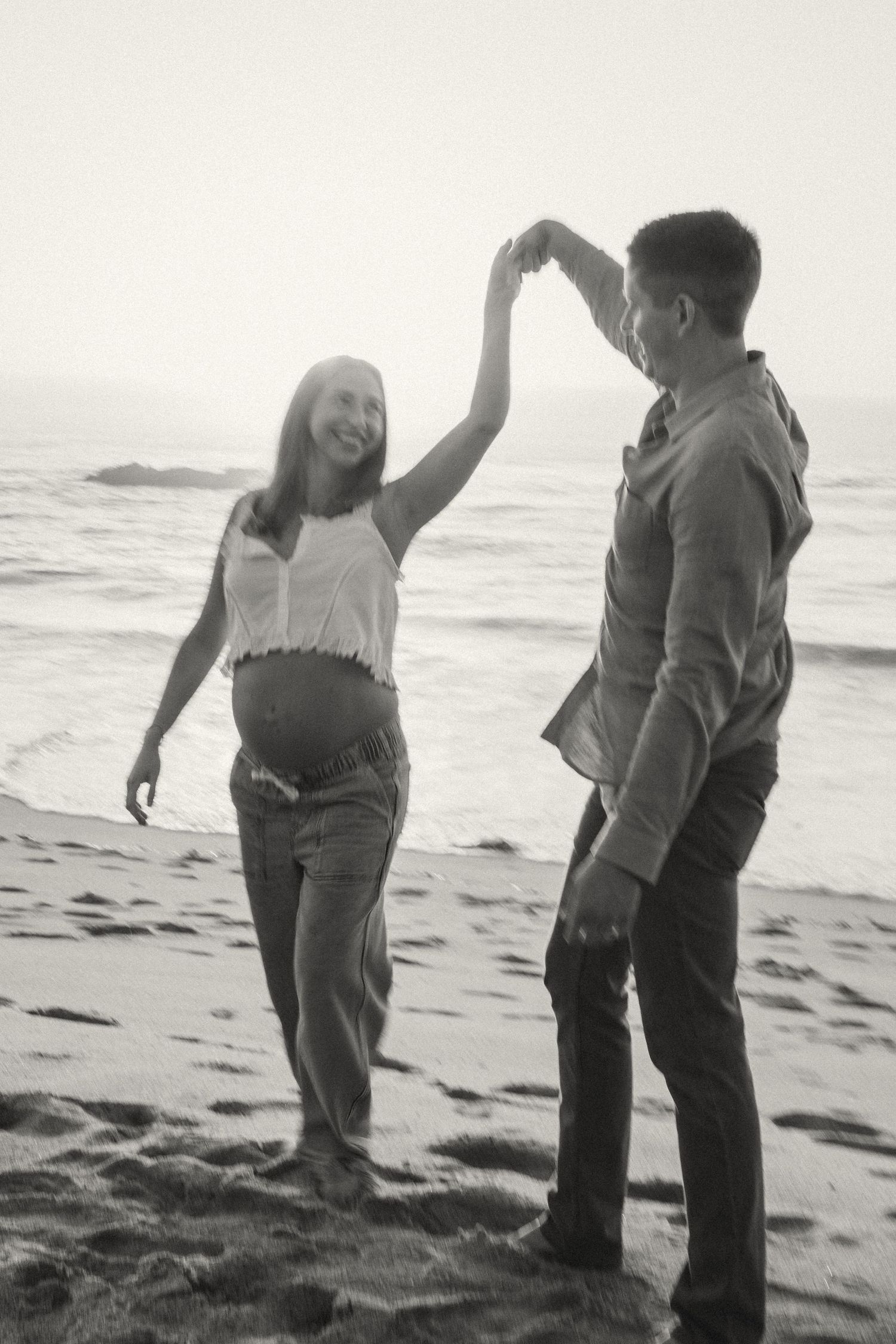 Black and white sequence of people bending down to examine something on a sandy beach.