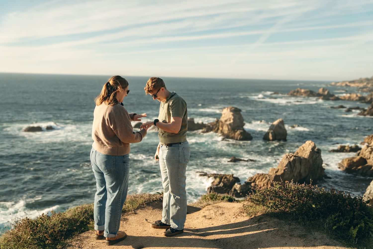 A scenic coastal engagement photoshoot at sunset overlooking the rugged California coastline and crashing waves.