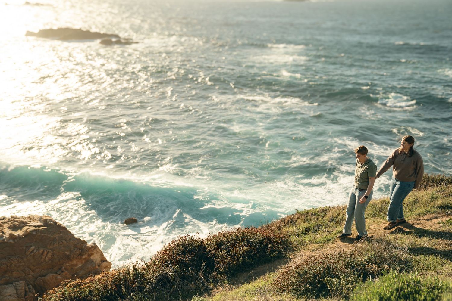Scenic coastal landscape with rocky cliffs and crashing waves along the shoreline during golden hour.