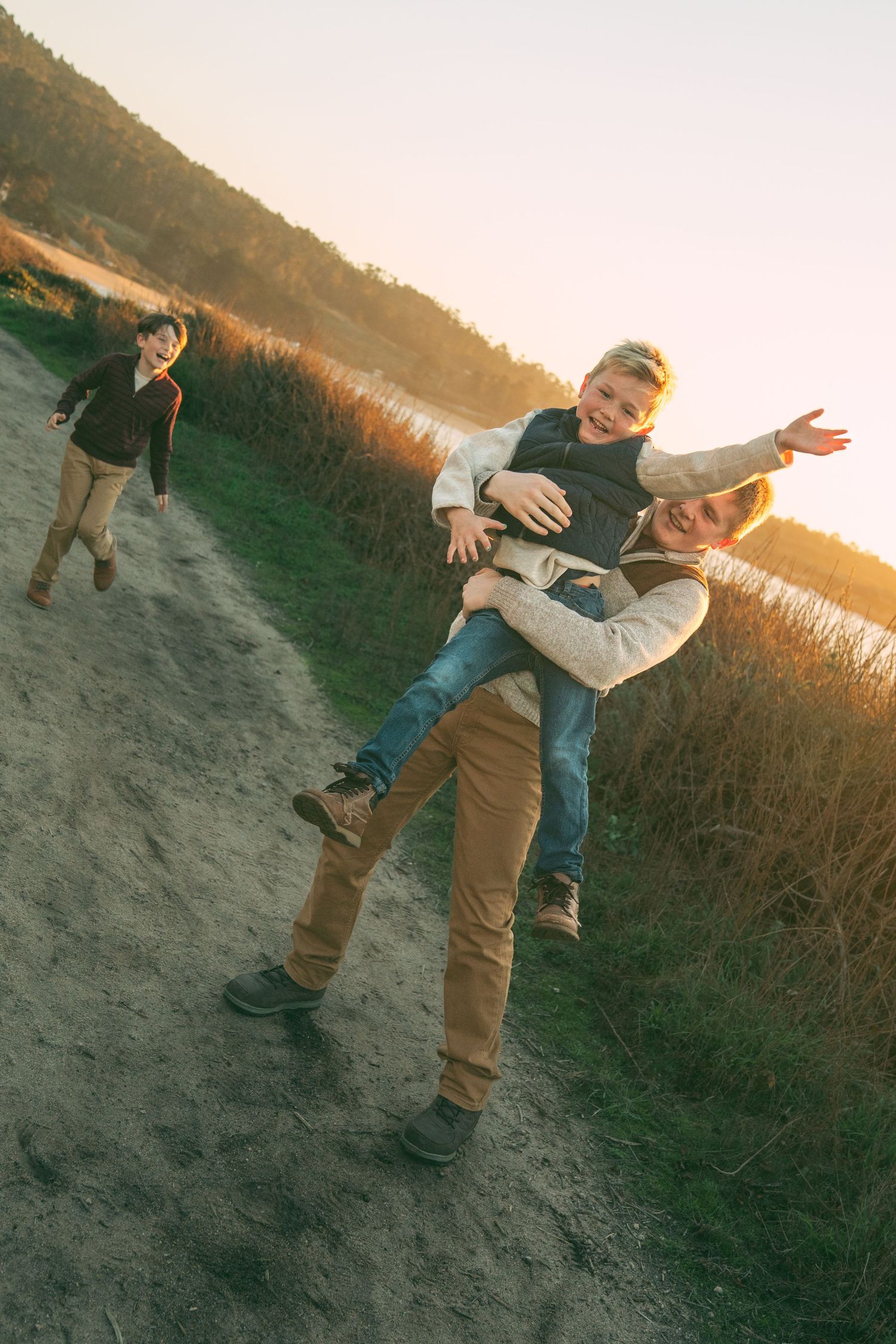 A series of playful poses captured at sunset in a grassy coastal area.