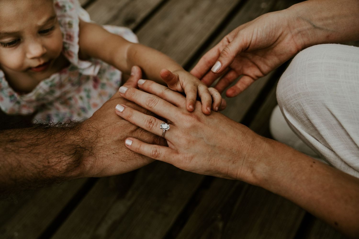 Close-up shot of hands touching on wooden deck surface.