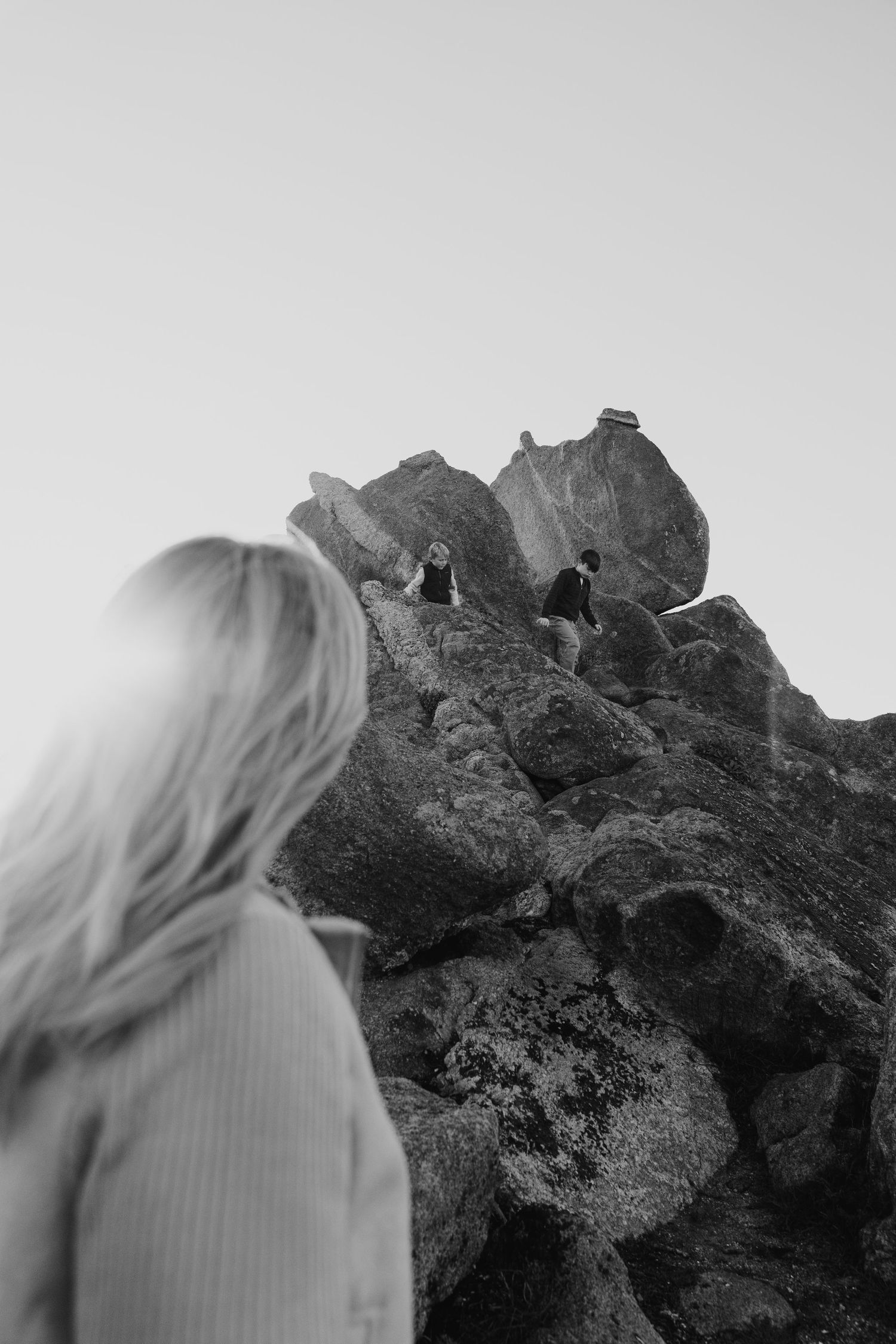 Mother watching her boys play in the Rocks at Carmel california beaches.