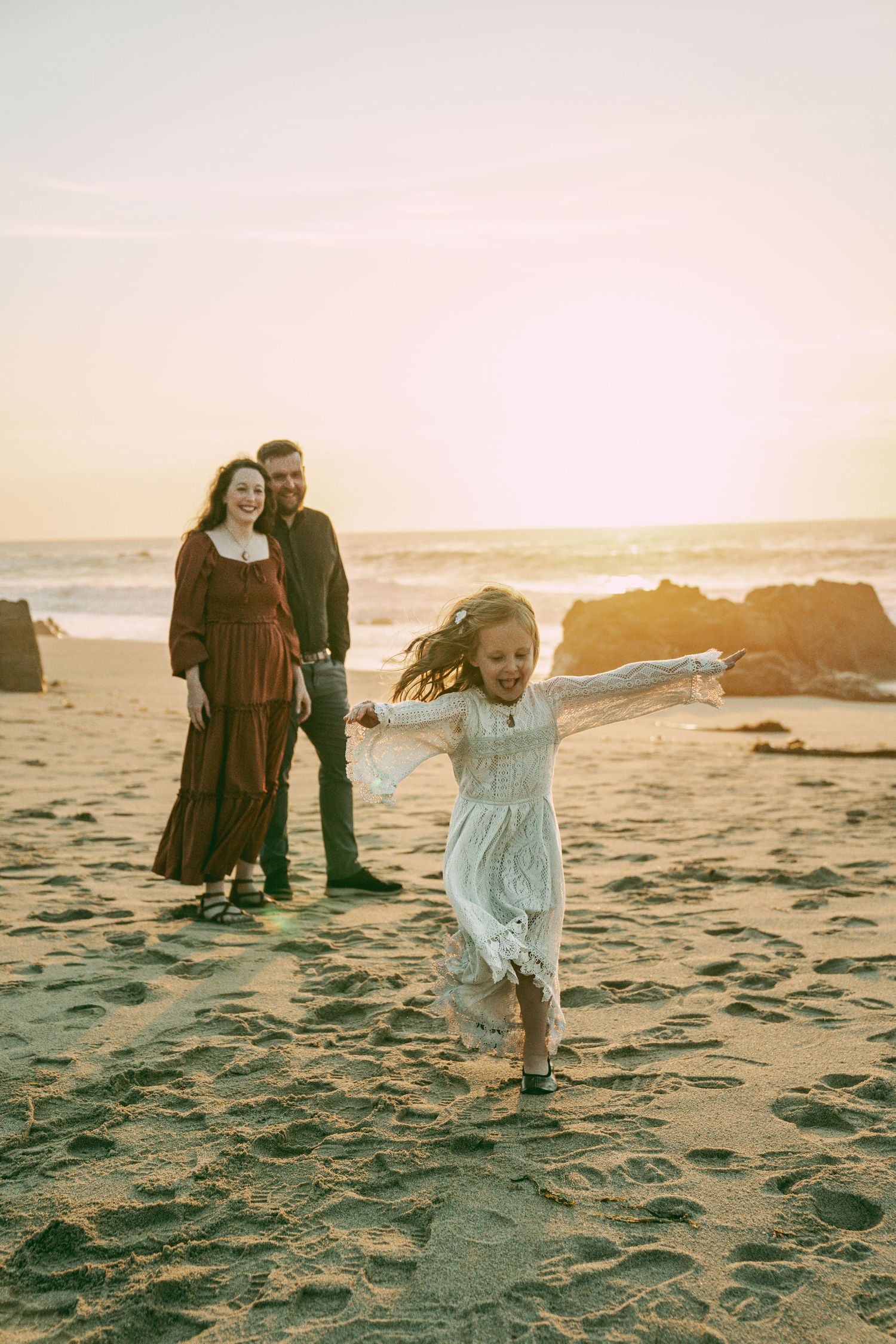 A couple walks together on a sandy beach at sunset with warm golden light creating a romantic atmosphere.