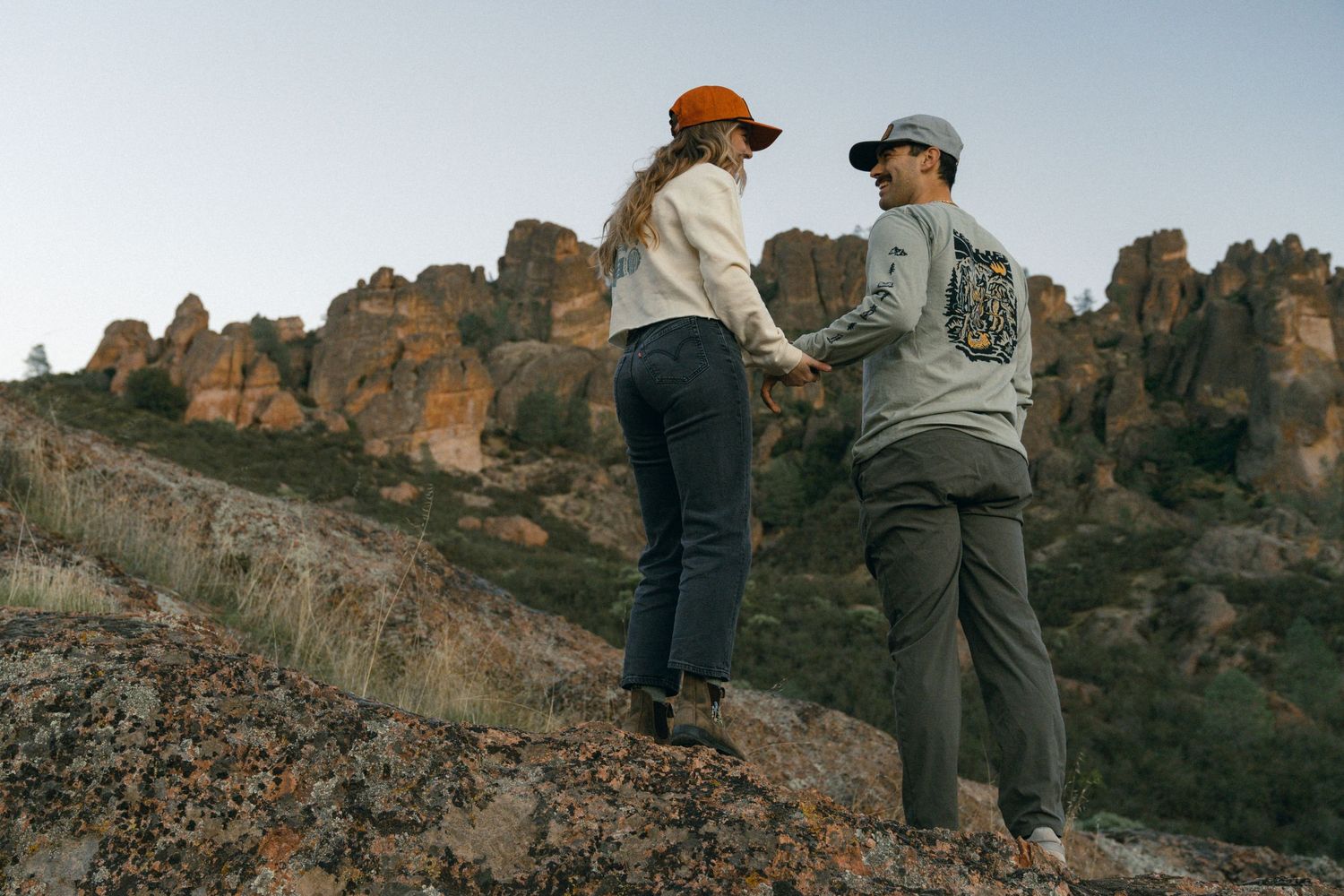 Two hikers admire a scenic rocky mountain landscape while standing on a ridge.