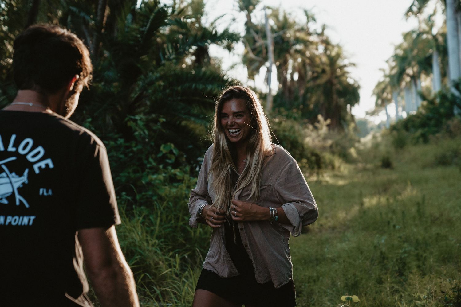 A candid moment of laughter and connection between two people surrounded by tropical greenery.