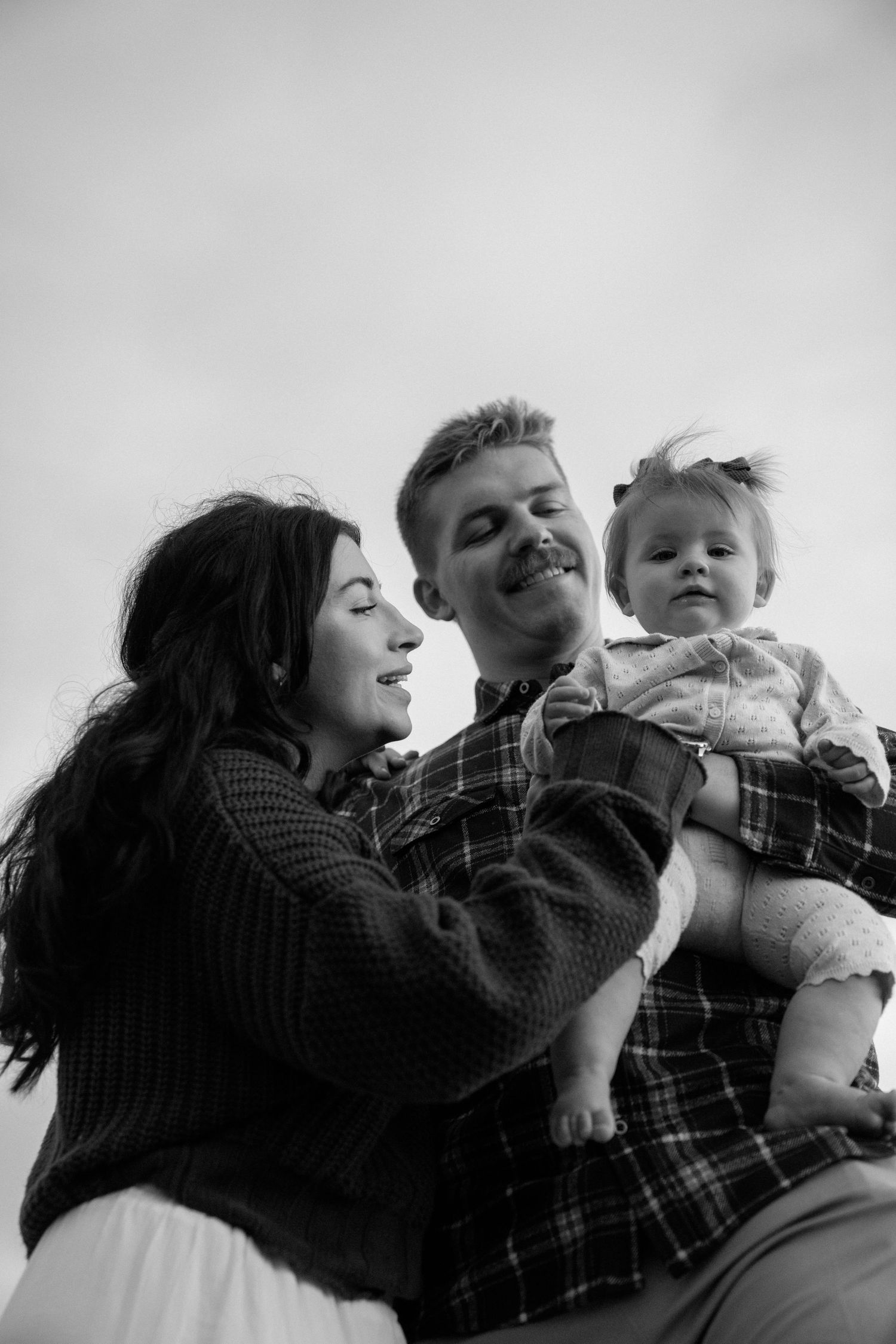 Playful family photos at Asilomar State Beach captured in black and white against a light background.