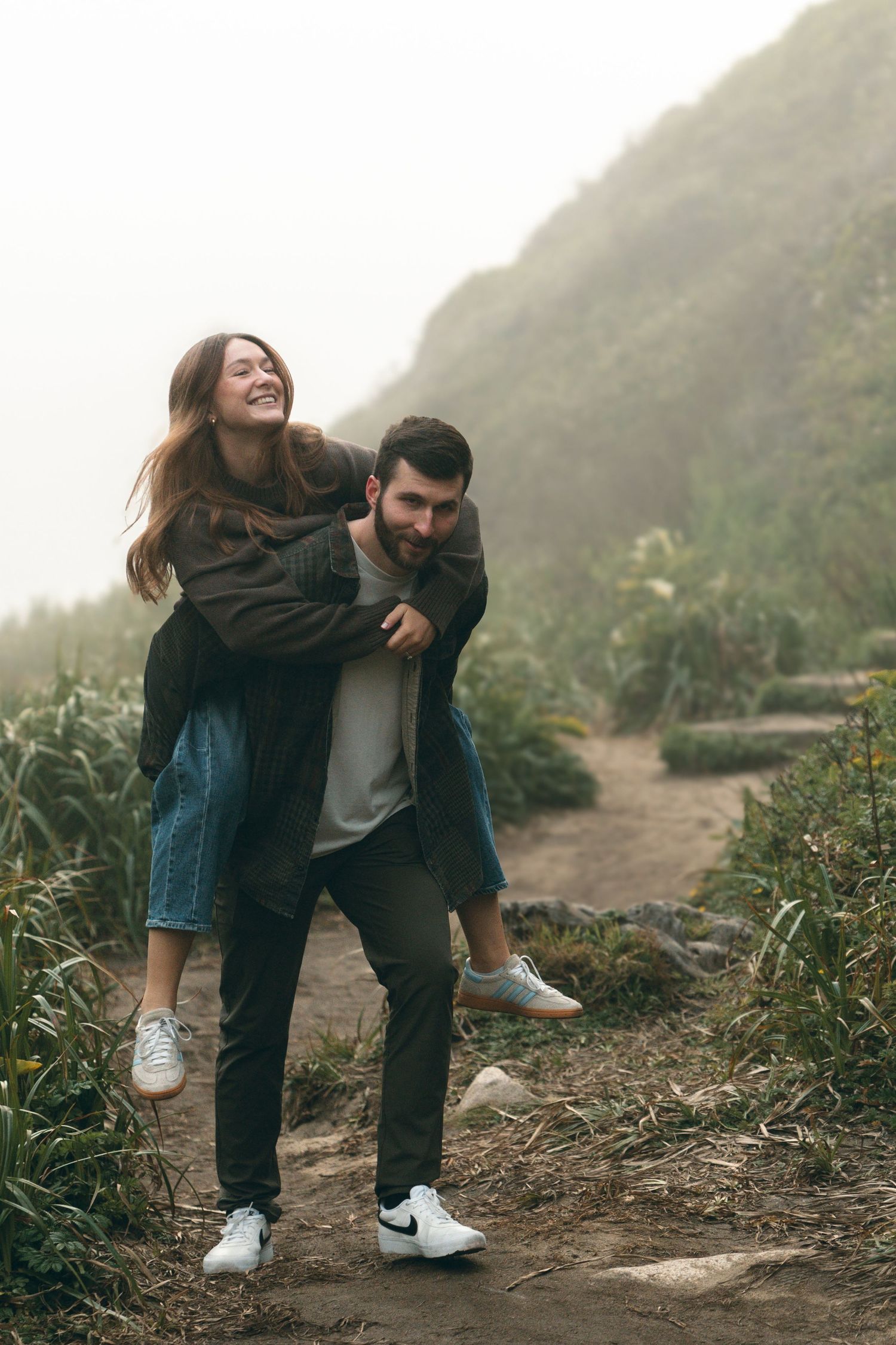 Couple sharing playful interactions on coastal hiking trail.