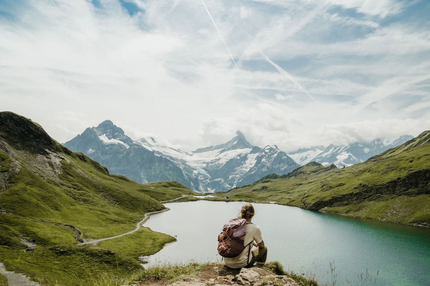 Stunning alpine lake landscape with snow-capped mountains and hikers enjoying the panoramic view.