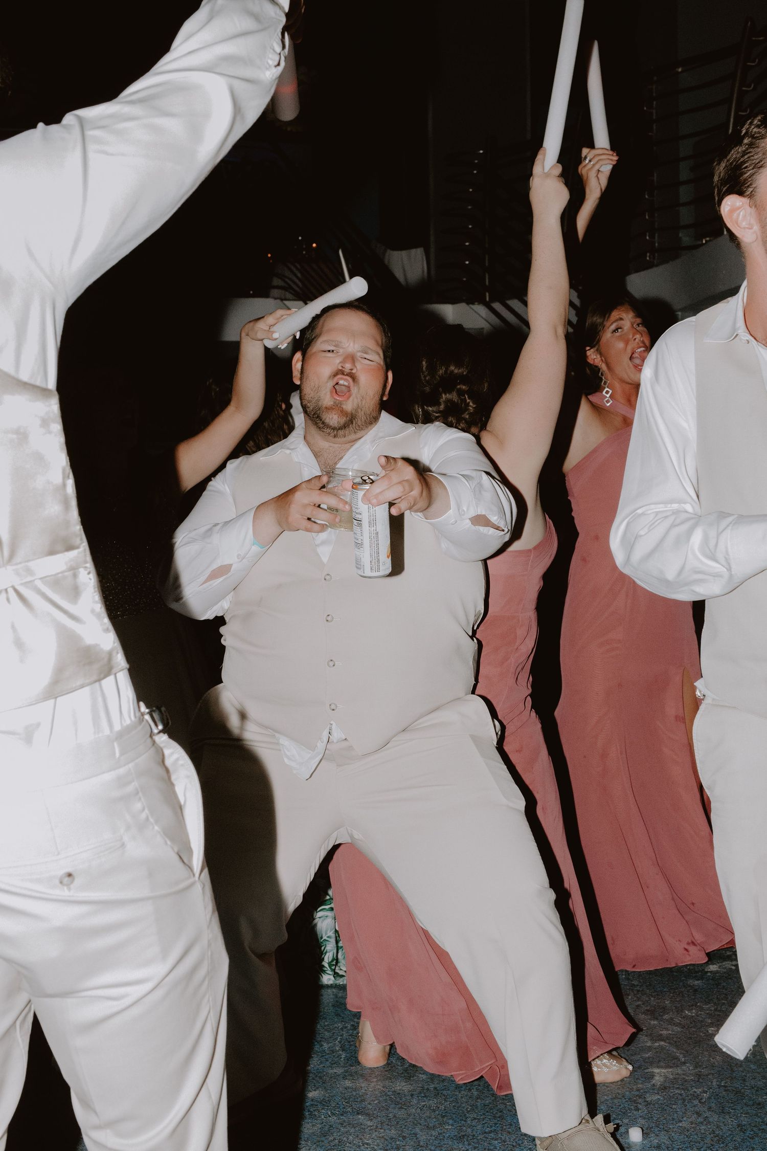 People in white attire dancing enthusiastically together at a celebration or party.