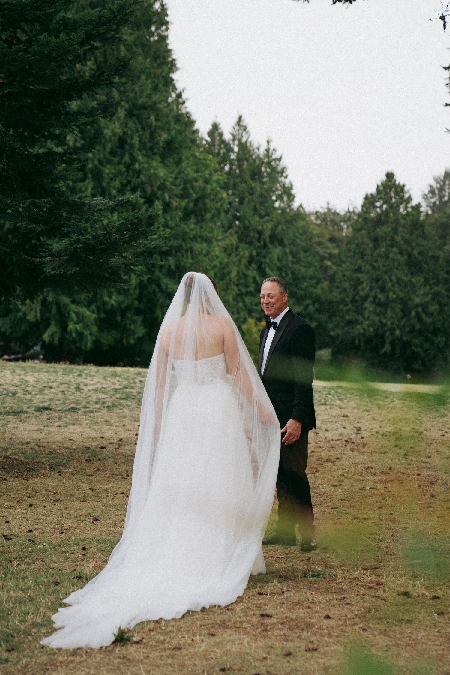 Wedding first look sequence showing bride in flowing white gown approaching groom in outdoor garden setting.