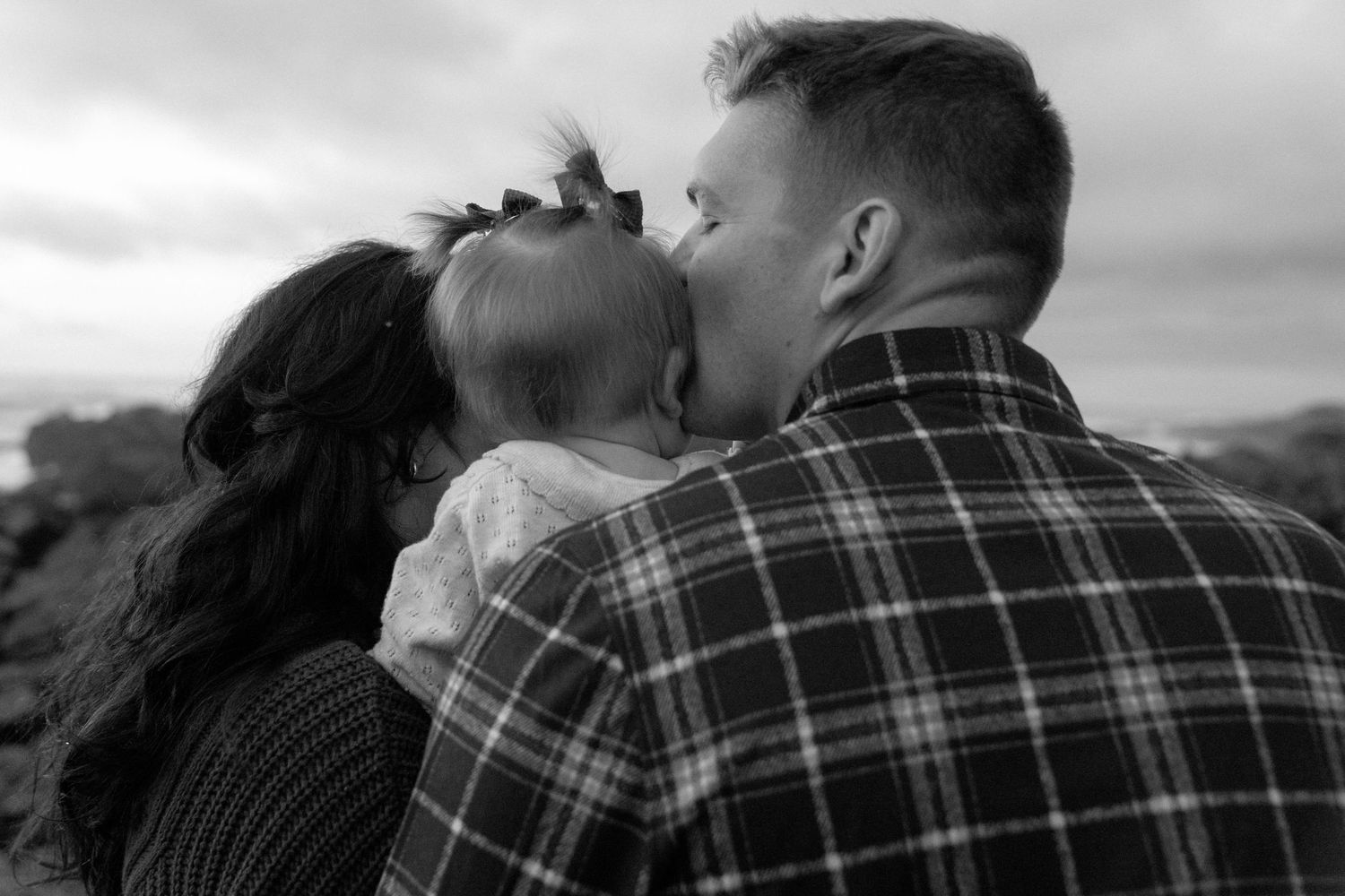 Black and white Family photos at Asilomar State Beach against dramatic coastal landscape.