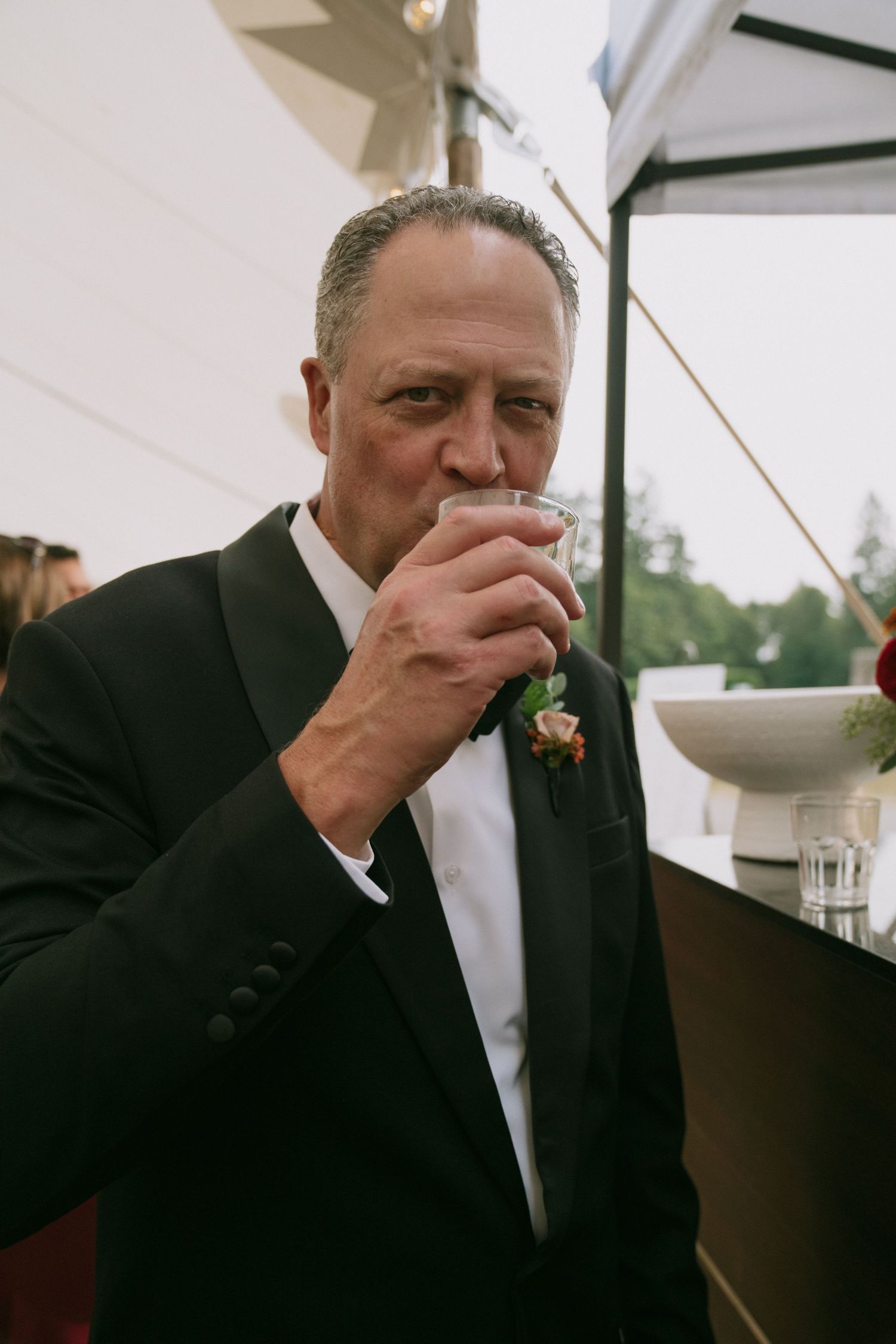 A man in a black suit wipes his eyes during an emotional moment at a wedding.