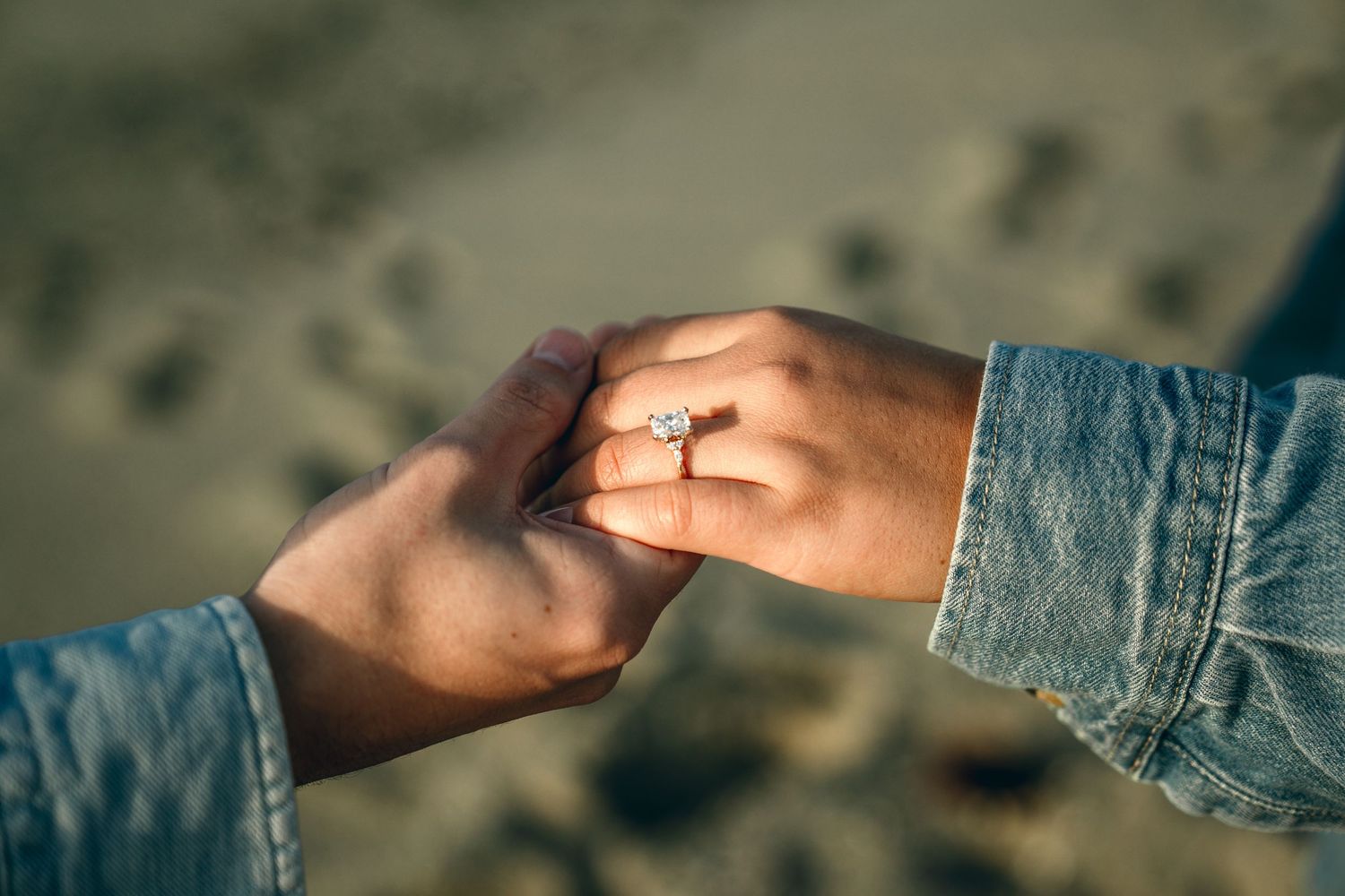 Close-up view of hands exchanging a small object in natural lighting with denim clothing visible.