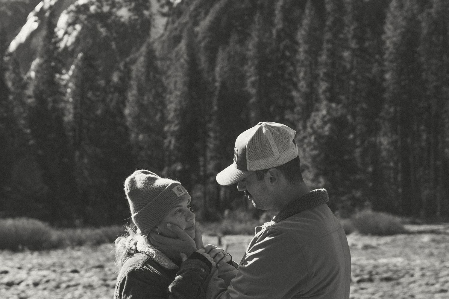 A tender moment shared between two people against a backdrop of mountain peaks.