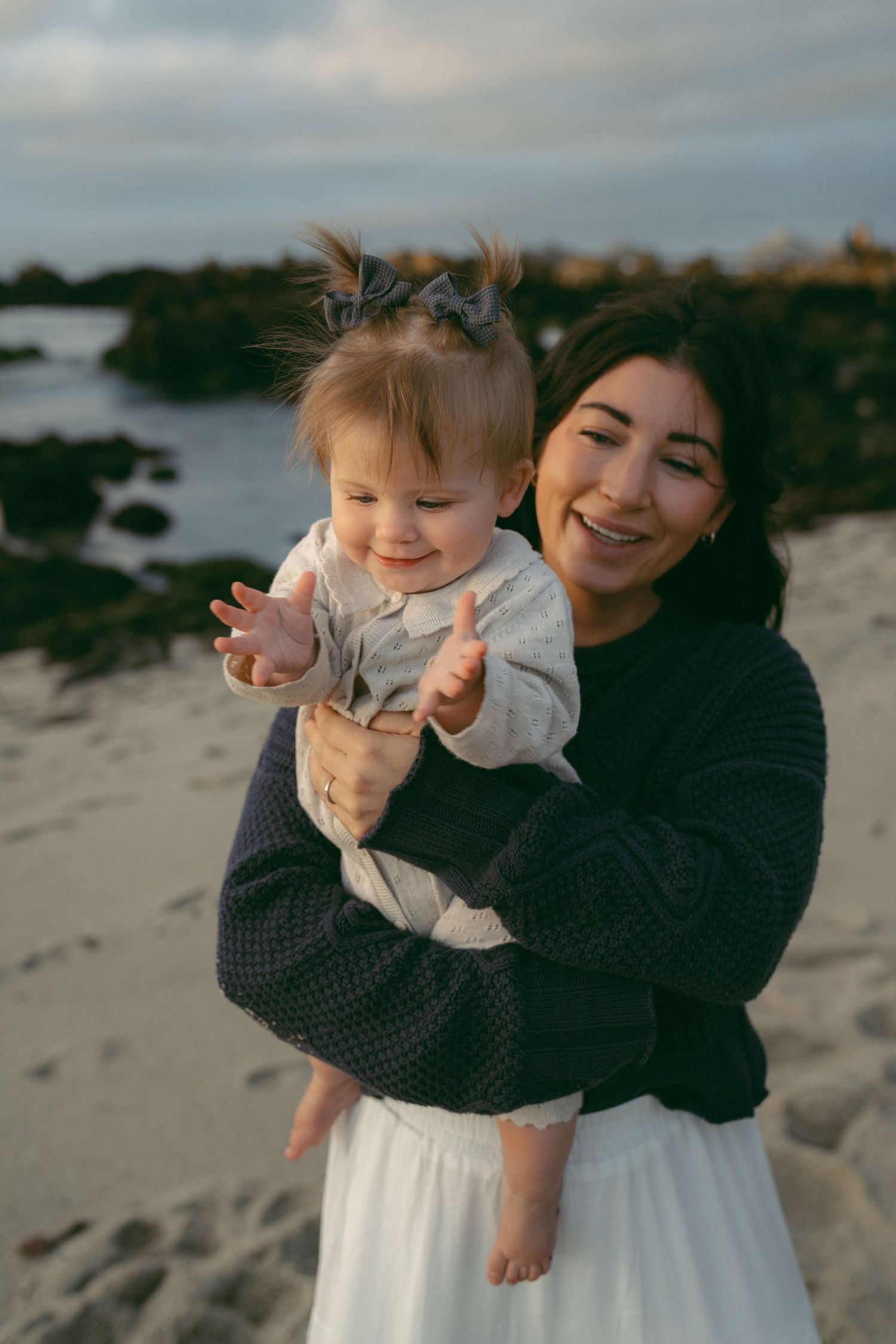 Playful interactions between family members on a sandy beach during golden hour.