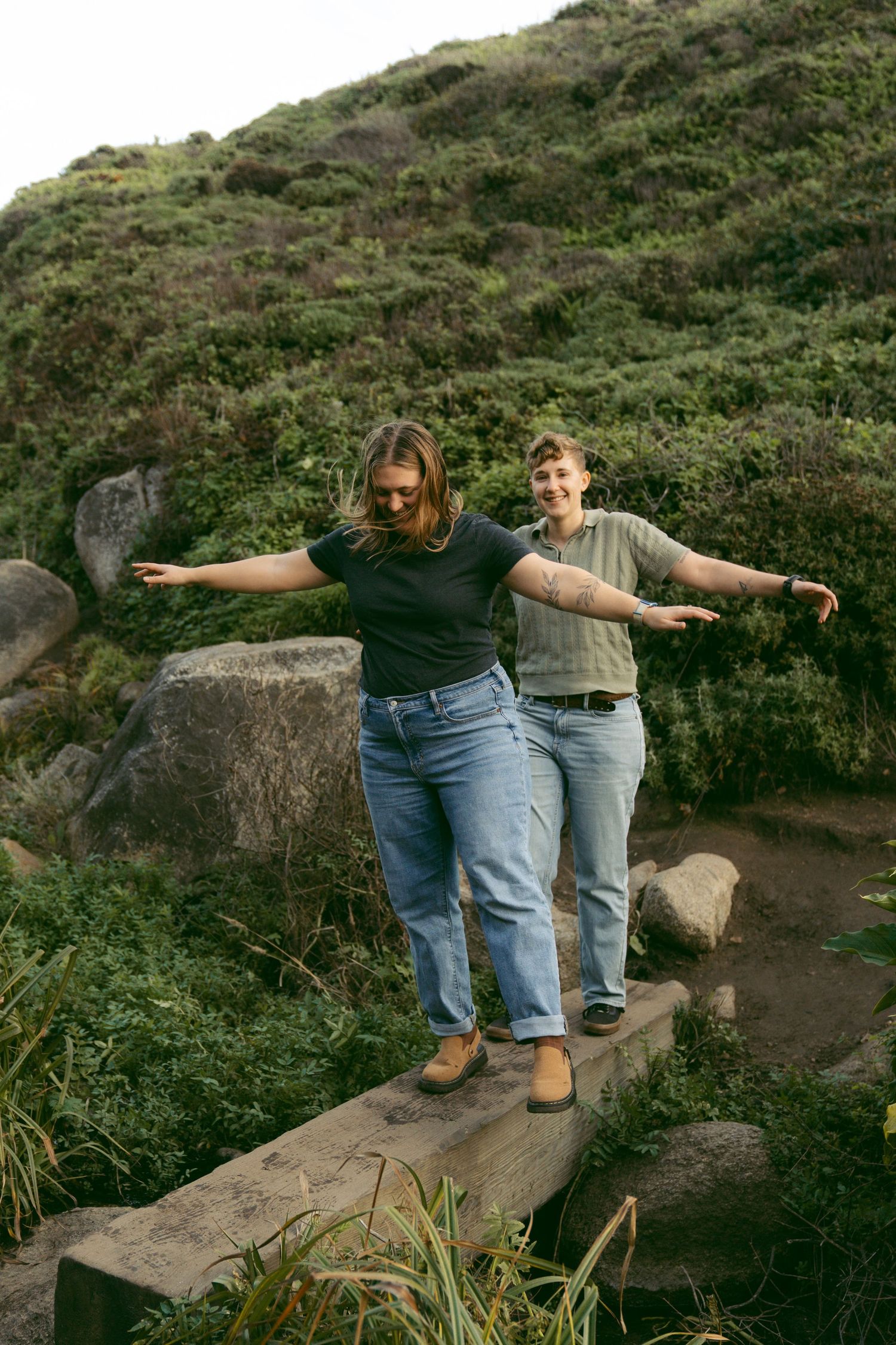 Couple balancing along a narrow bridge in Big Sur.