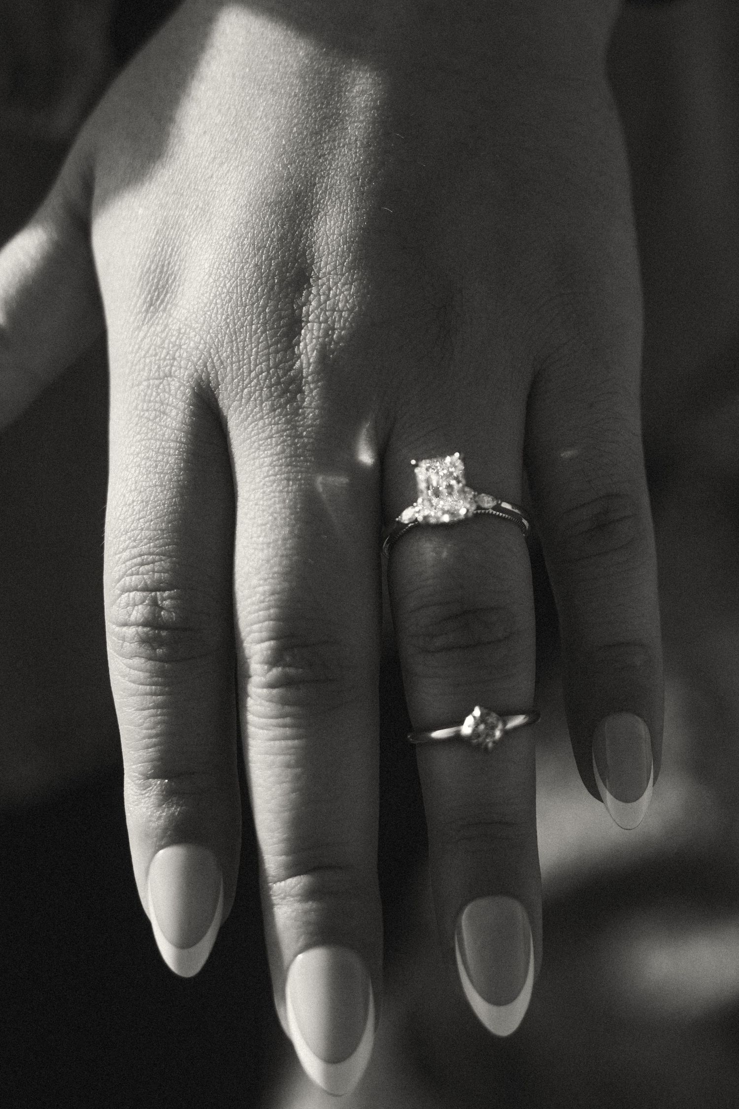 A series of black and white close-up photos showing a diamond engagement ring on a hand from different angles.