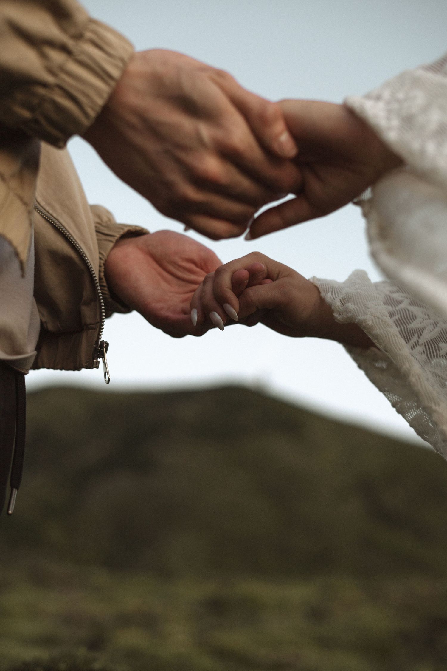 Couple exchanging wedding rings outdoors with green hills in the background during an elopement ceremony.