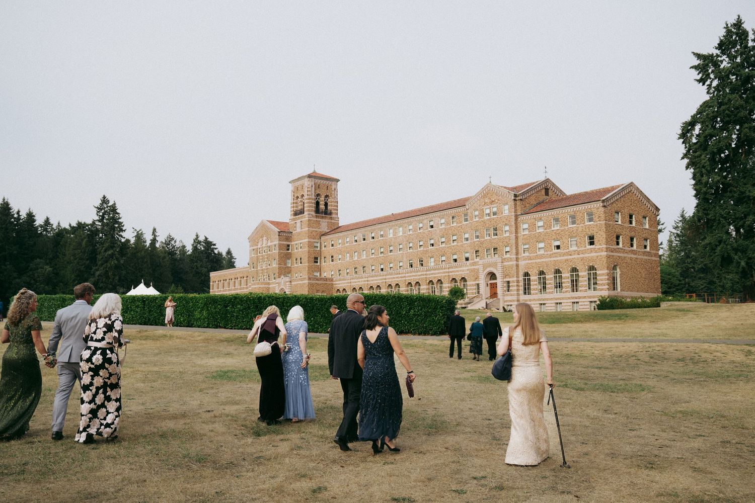 A panoramic collage of wedding guests gathered on a grassy lawn outside a grand historic stone building on a sunny day.