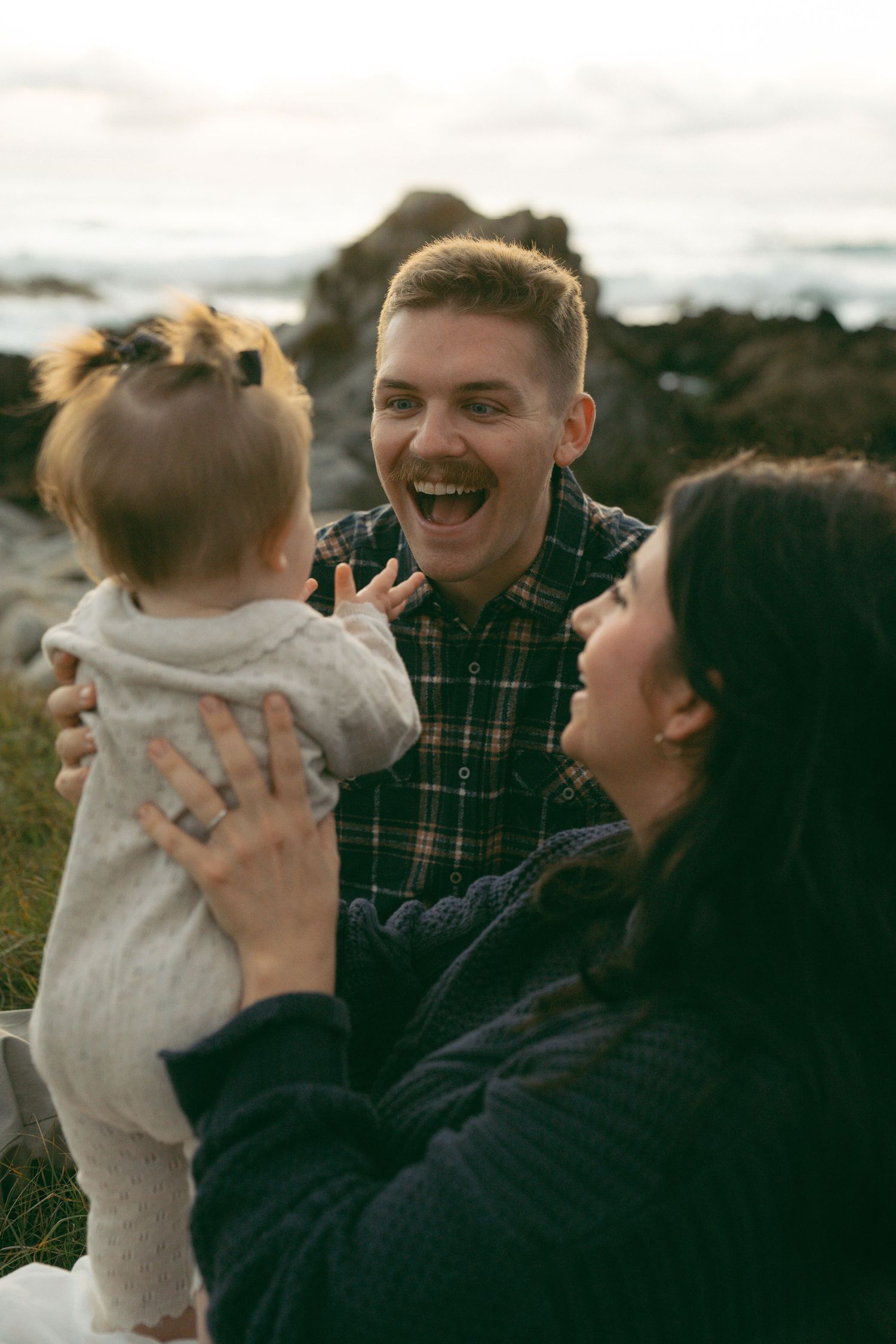 Candid Family photos at Asilomar State Beach captured on a scenic beach with cliffs in the background during golden hour.