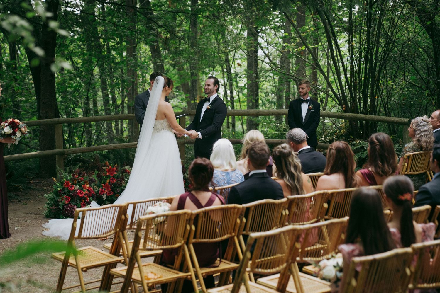 Outdoor wedding ceremony setup in a lush forest with wooden chairs and natural greenery creating a romantic atmosphere.