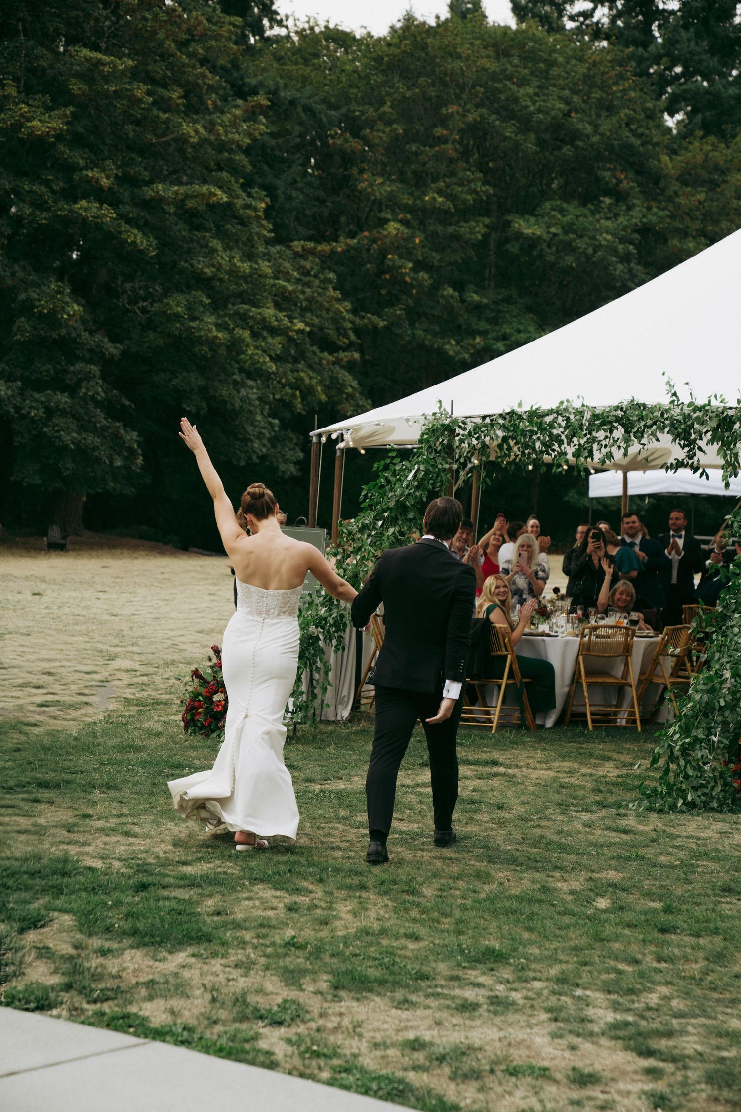 A wedding celebration on an outdoor lawn with white tents and guests enjoying the festivities.