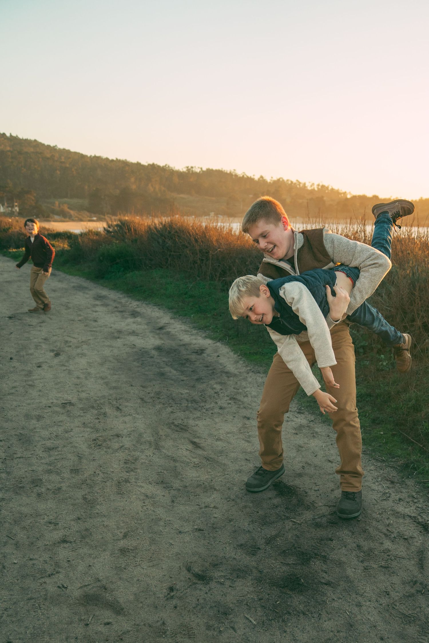 A sequence of someone performing stretching exercises on a sandy trail during golden hour.