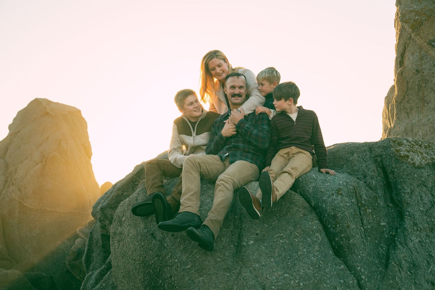 A group relaxes together on rocky cliffs during golden hour sunset.