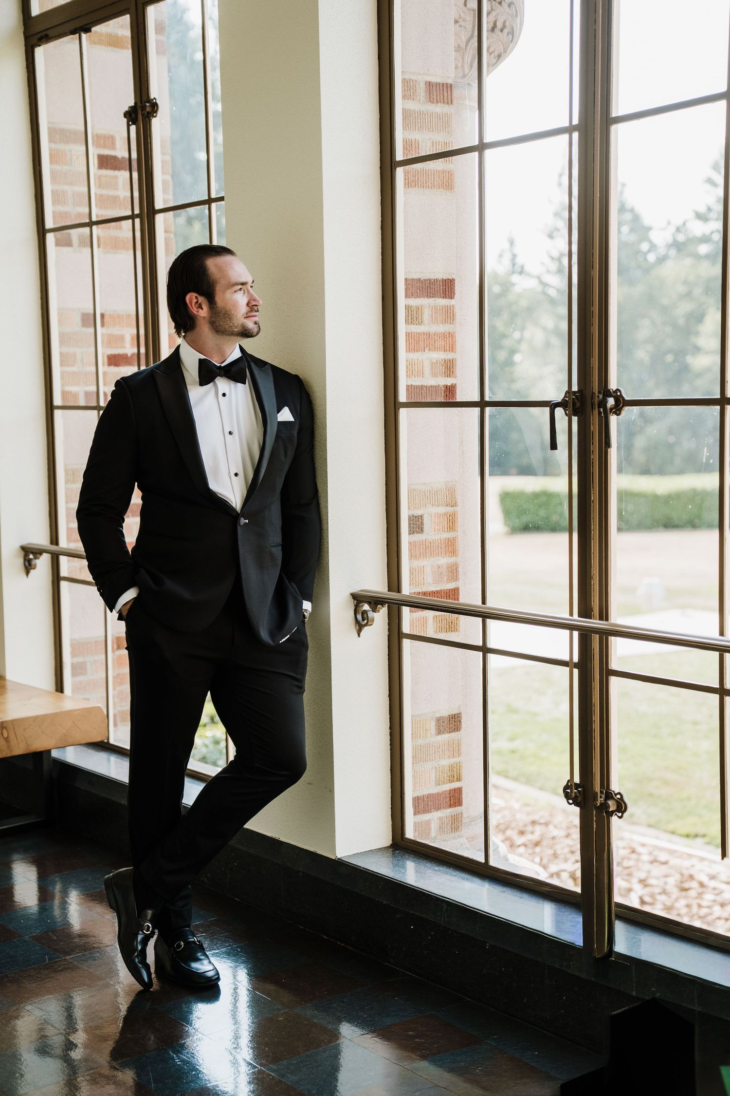 Groom in black tuxedo with shadows from large windows at The Lodge at St. Edward Park in Kenmore WA.