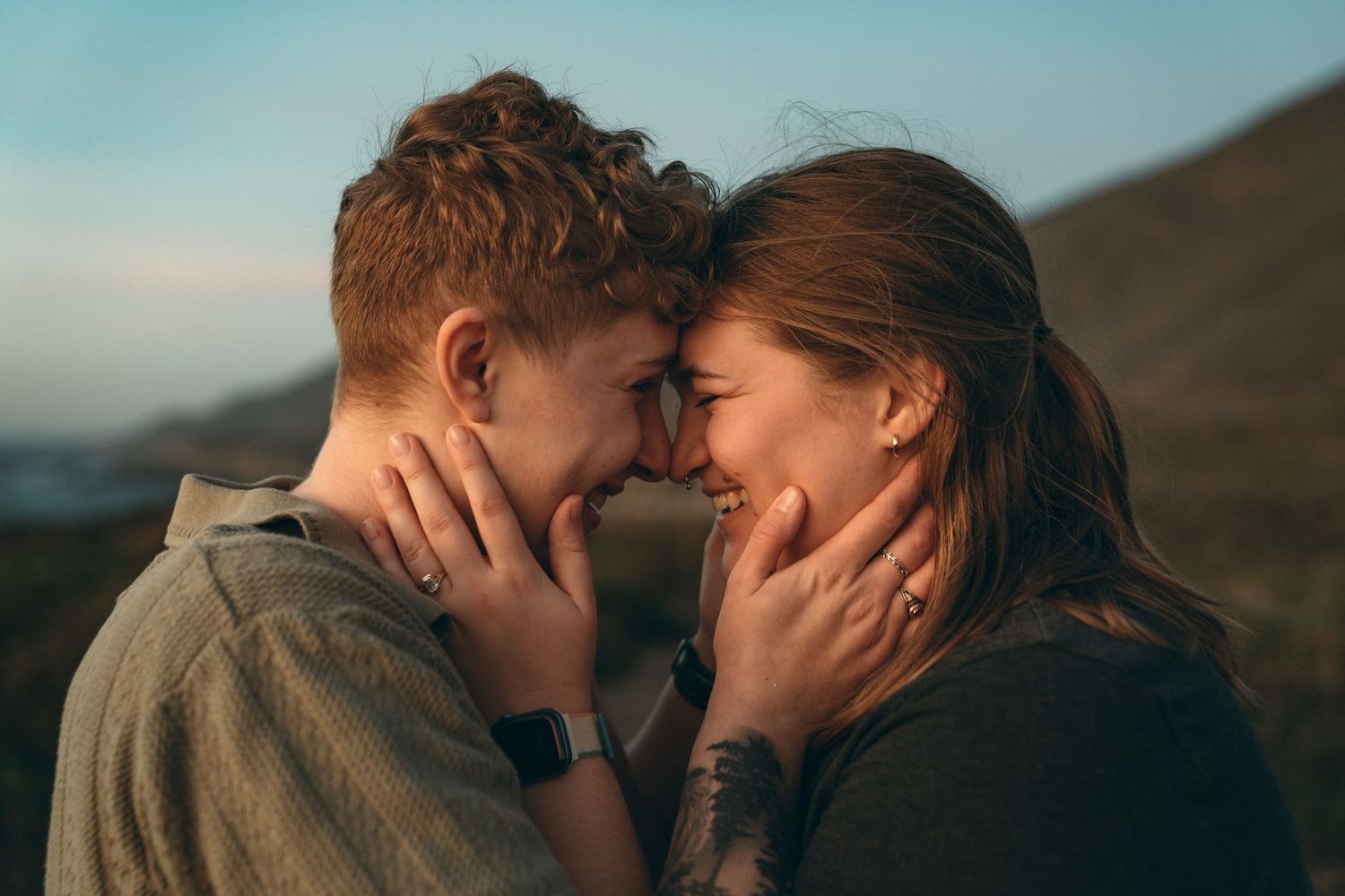Romantic sunset moment shared between couple with mountains in background.