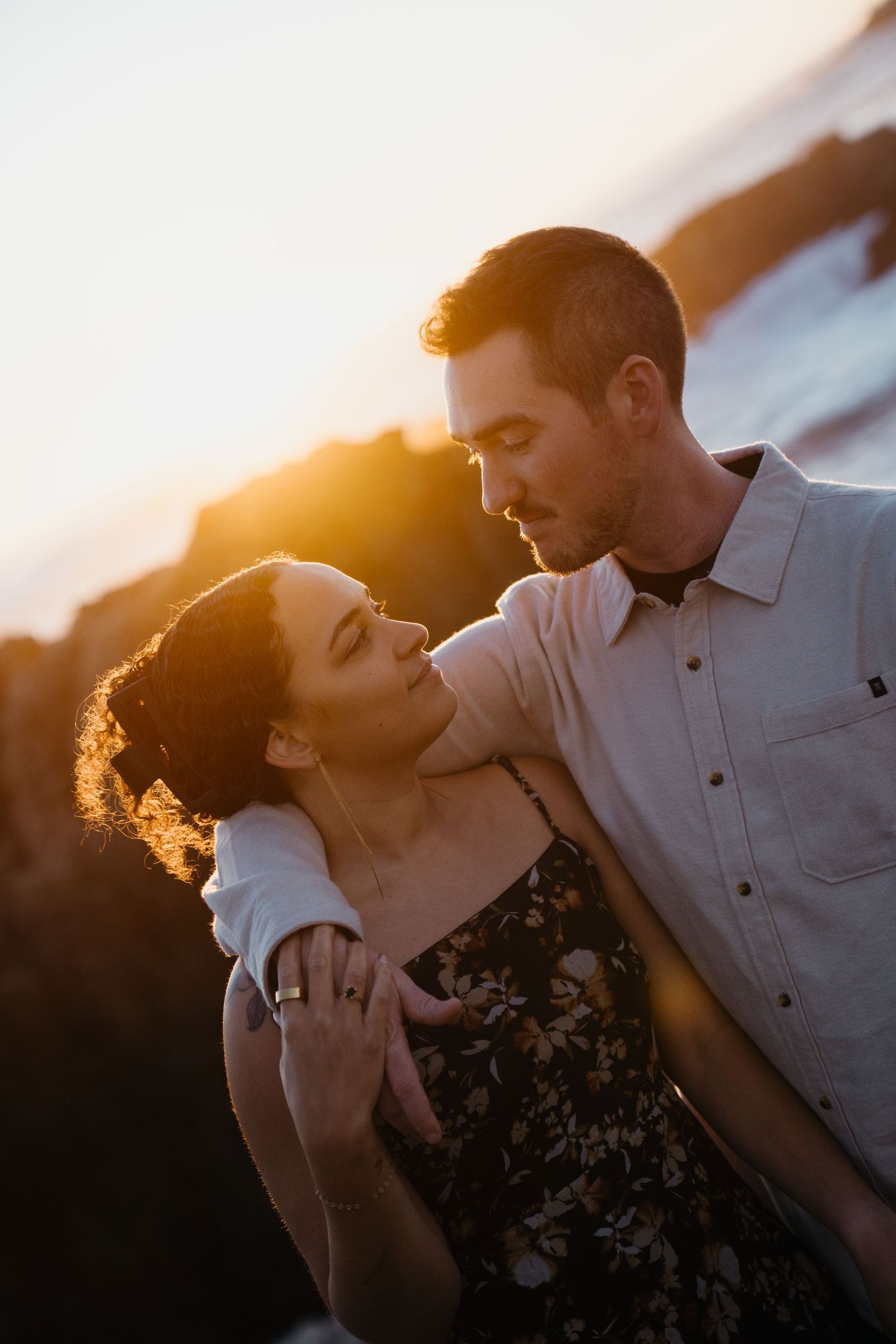 A couple embraces in a romantic sunset silhouette, creating a dreamy backlit portrait against the golden sky.