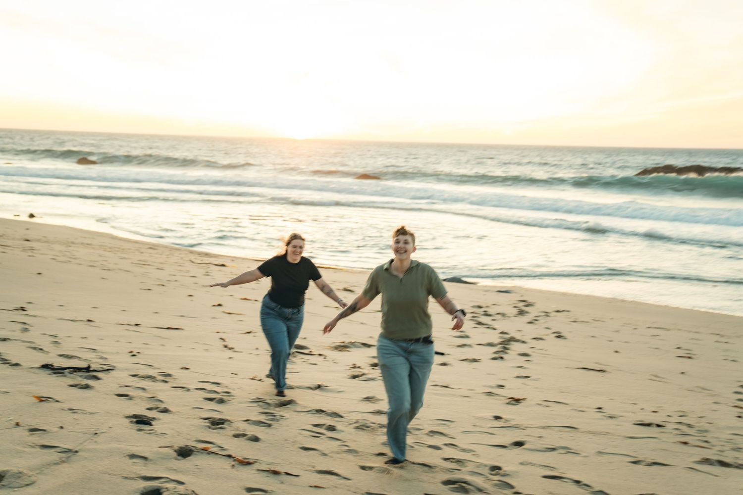 Couple running and playing together on an empty beach at golden hour.