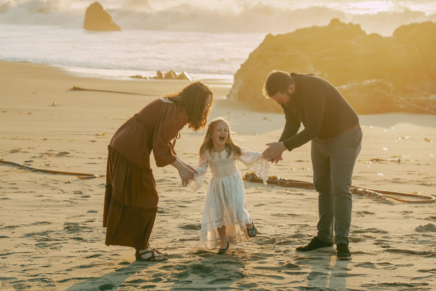 People enjoying sunset at beach while searching for seashells along the shoreline during golden hour.