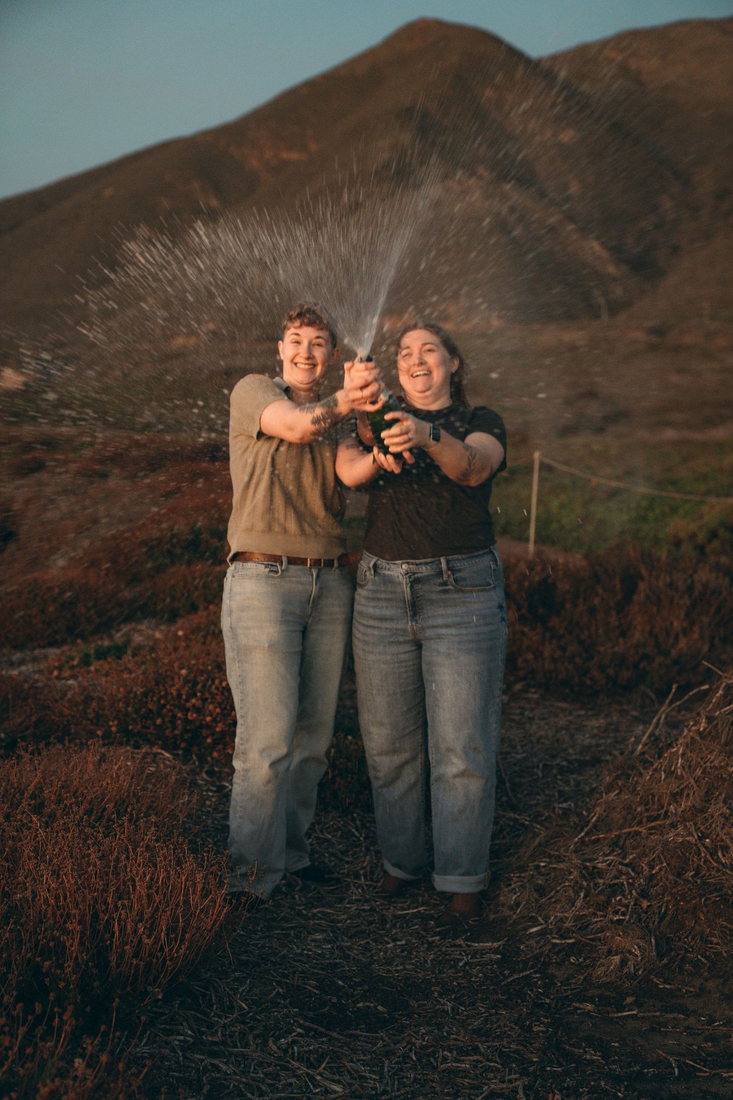 Friends posing together against mountainous backdrop during sunset.
