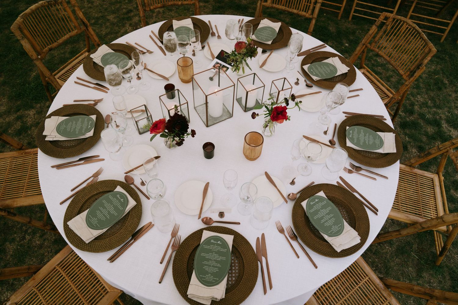 Elegant round reception tables set with white linens and place settings in a rustic venue.