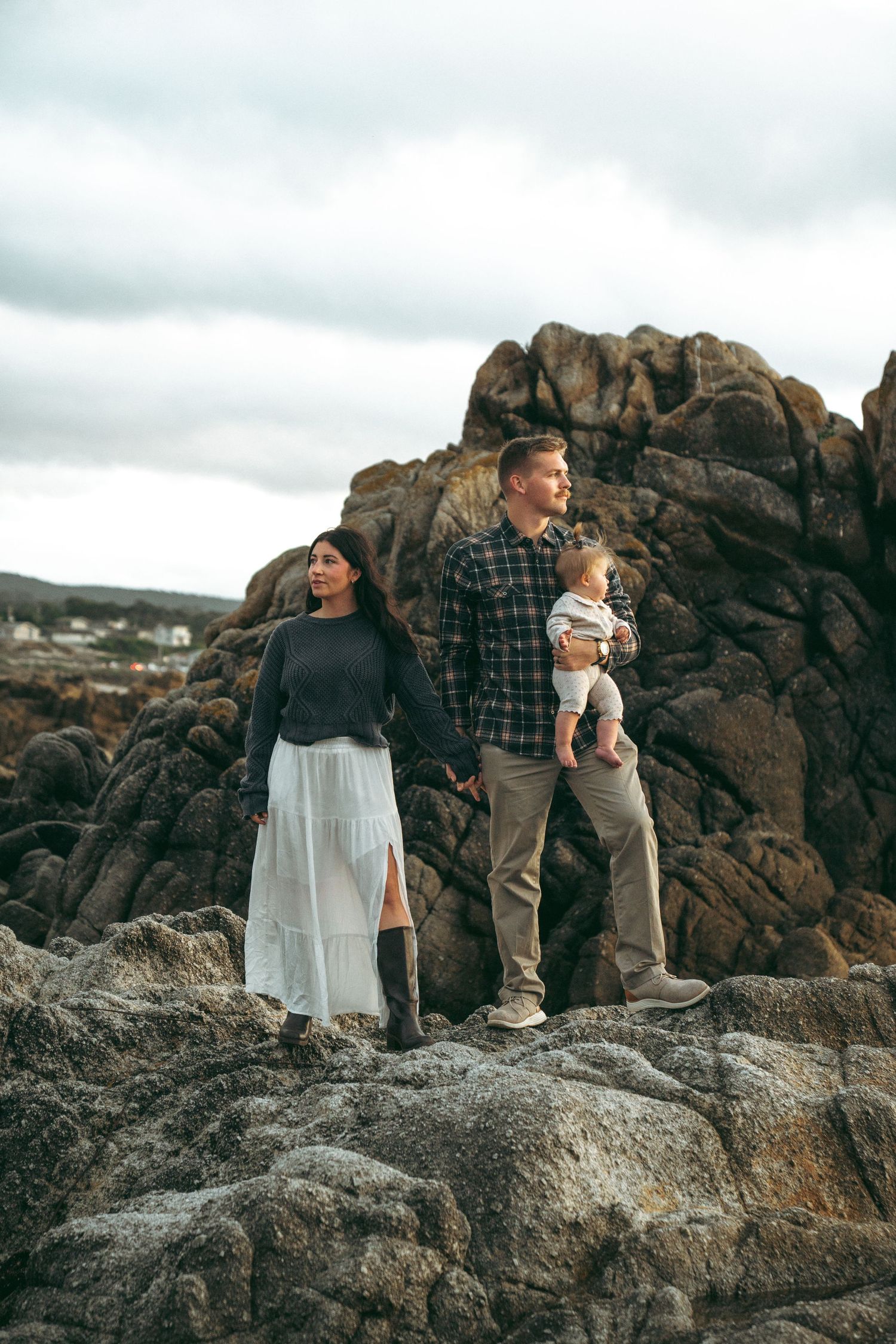 Family photos at Asilomar State Beach on rocky coastal terrain during an overcast day at the beach.