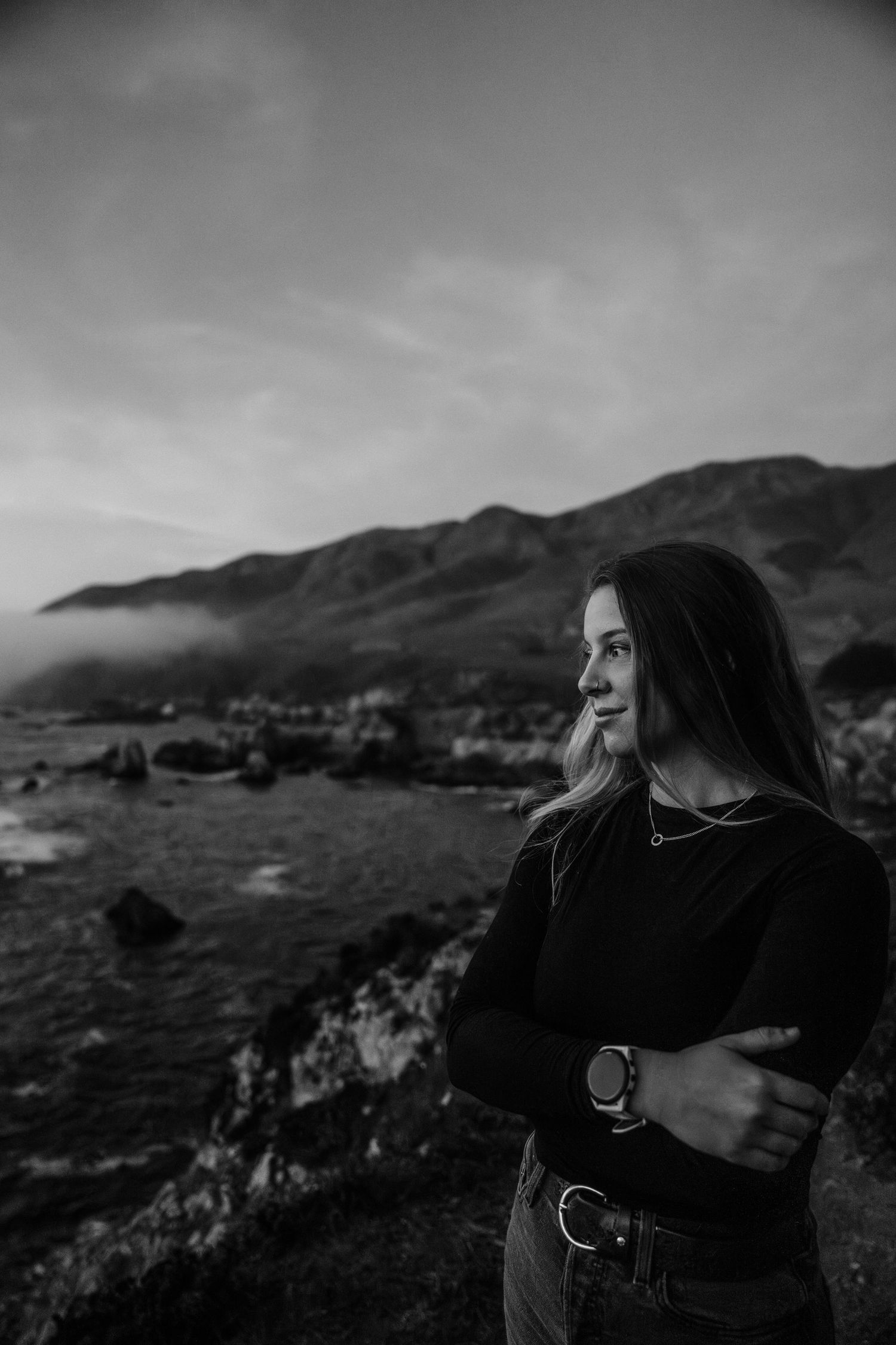 Dramatic black and white coastal photography along rocky cliffs at sunset.