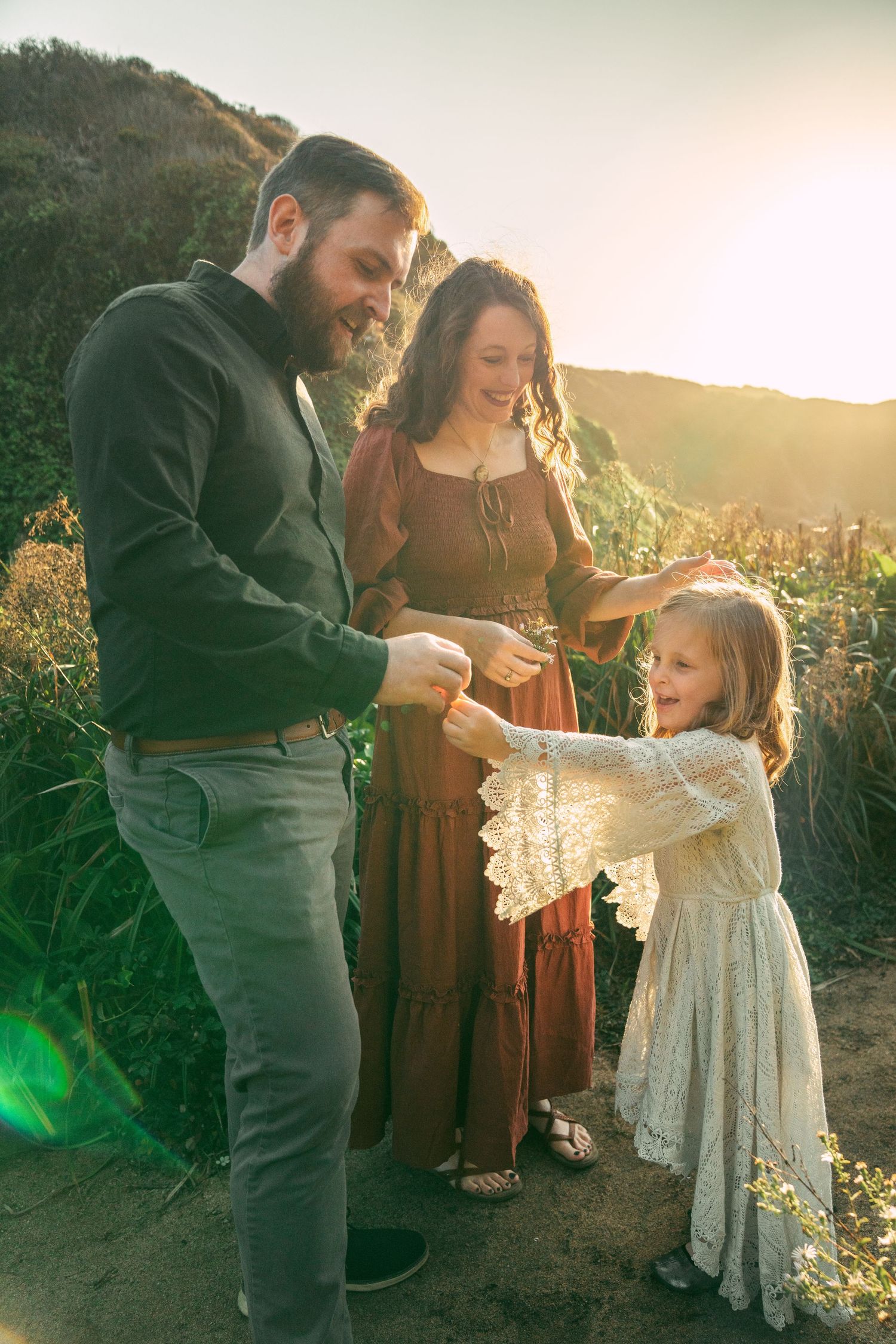 Family enjoying a tender moment together at sunset in an outdoor setting with mountains in the background.